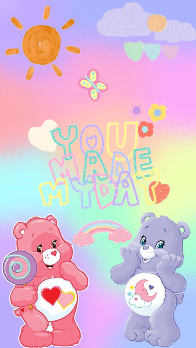 彩虹熊 桌布 壁紙 — 兩隻色彩繽紛的Care Bears帶著愛心和棒棒糖漂浮在粉彩天空，有太陽雲和彩虹。