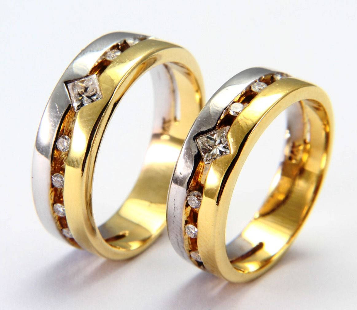 Wedding Rings 桌布 壁紙 — 兩隻金色和銀色的結婚戒指，帶有鑽石點綴，並排放在白色表面上。