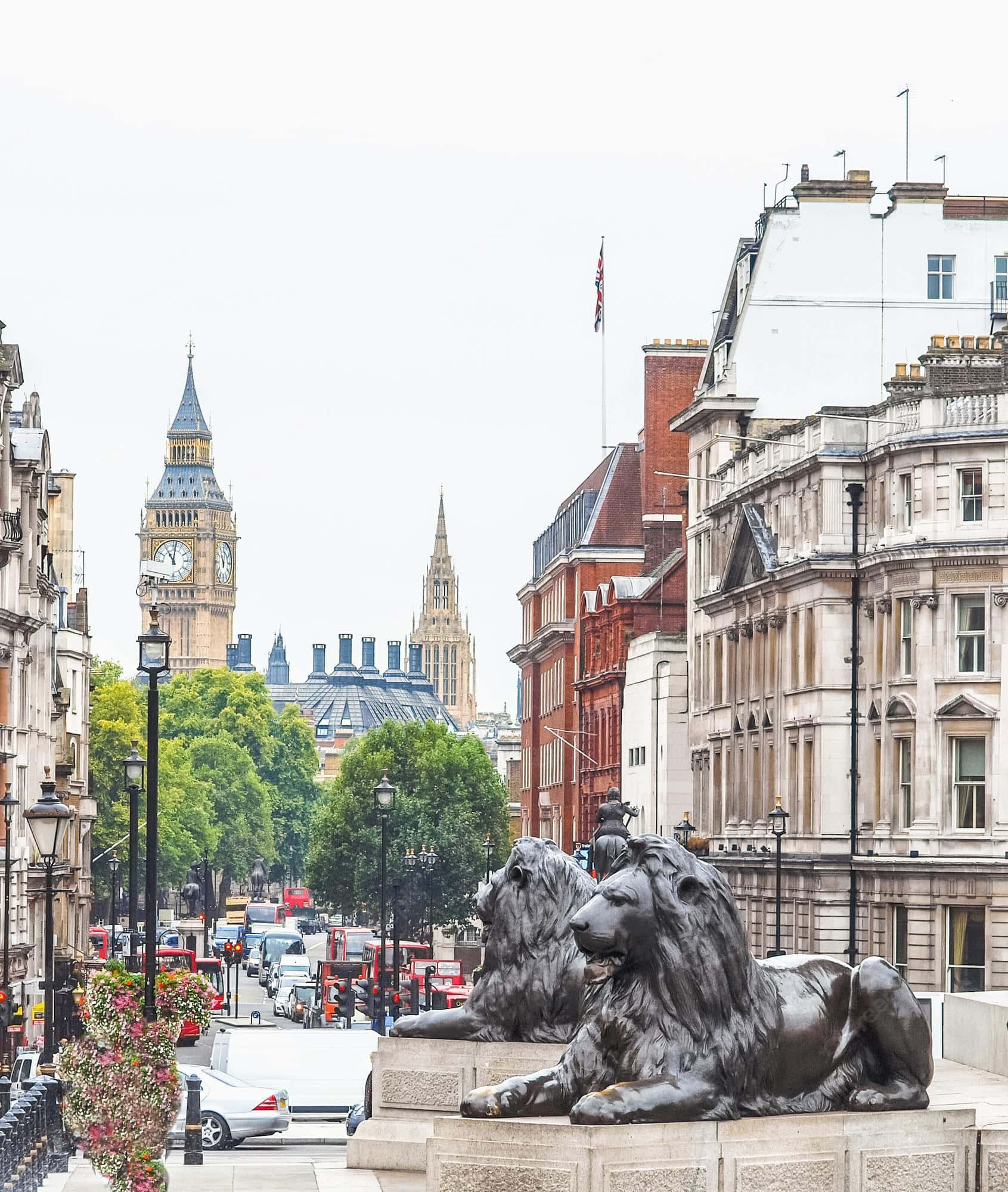 England 桌布 壁紙 — 兩隻青銅獅子守衛著倫敦一條街道，遠處可見大笨鐘和國會大廈，天空多雲。