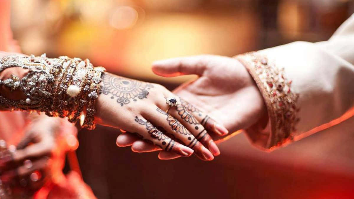 Marriage 桌布 壁紙 — 兩隻飾有精緻指甲花彩繪和珠寶的手，在溫暖發光的擁抱中輕輕觸碰。