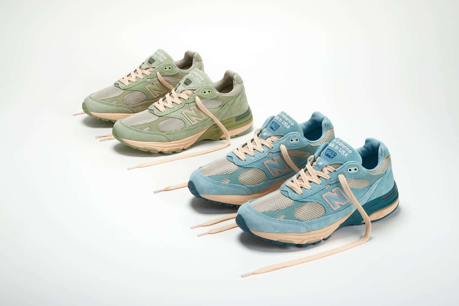 New Balance 桌布 壁紙 — 兩雙 New Balance 運動鞋，採用柔和綠色和藍色調，搭配米色鞋帶，對角排列在潔白背景上。