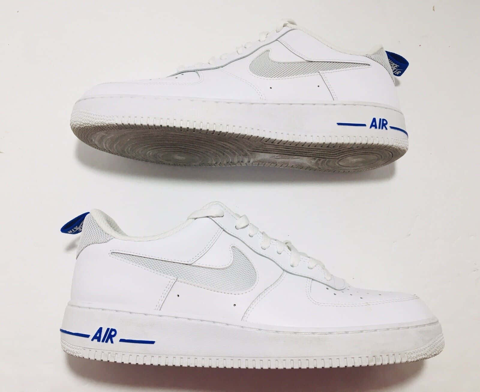 Nike Air Force 桌布 壁紙 — 兩雙帶有藍色點綴的白色Nike Air Force 1運動鞋，從頂部和側面展示在純白色背景上。