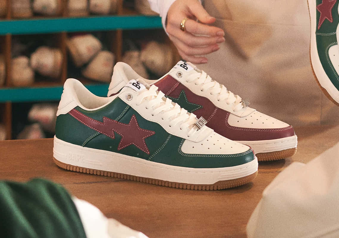 Bape 動態 桌布 壁紙 — 兩雙復古風格運動鞋，帶有綠色和栗色星星設計，展示在舒適商店環境的木製櫃檯上。