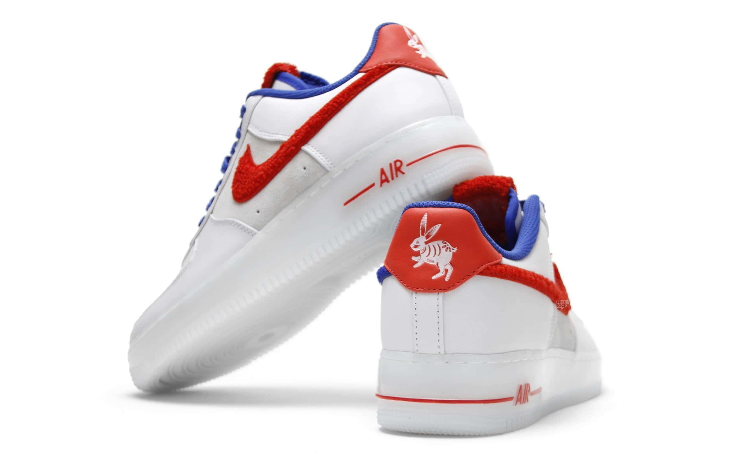 桌布 壁紙 — 兩雙白色Nike Air Force 1運動鞋，帶有紅藍色點綴和鞋跟上的兔子標誌，背景為純白色。