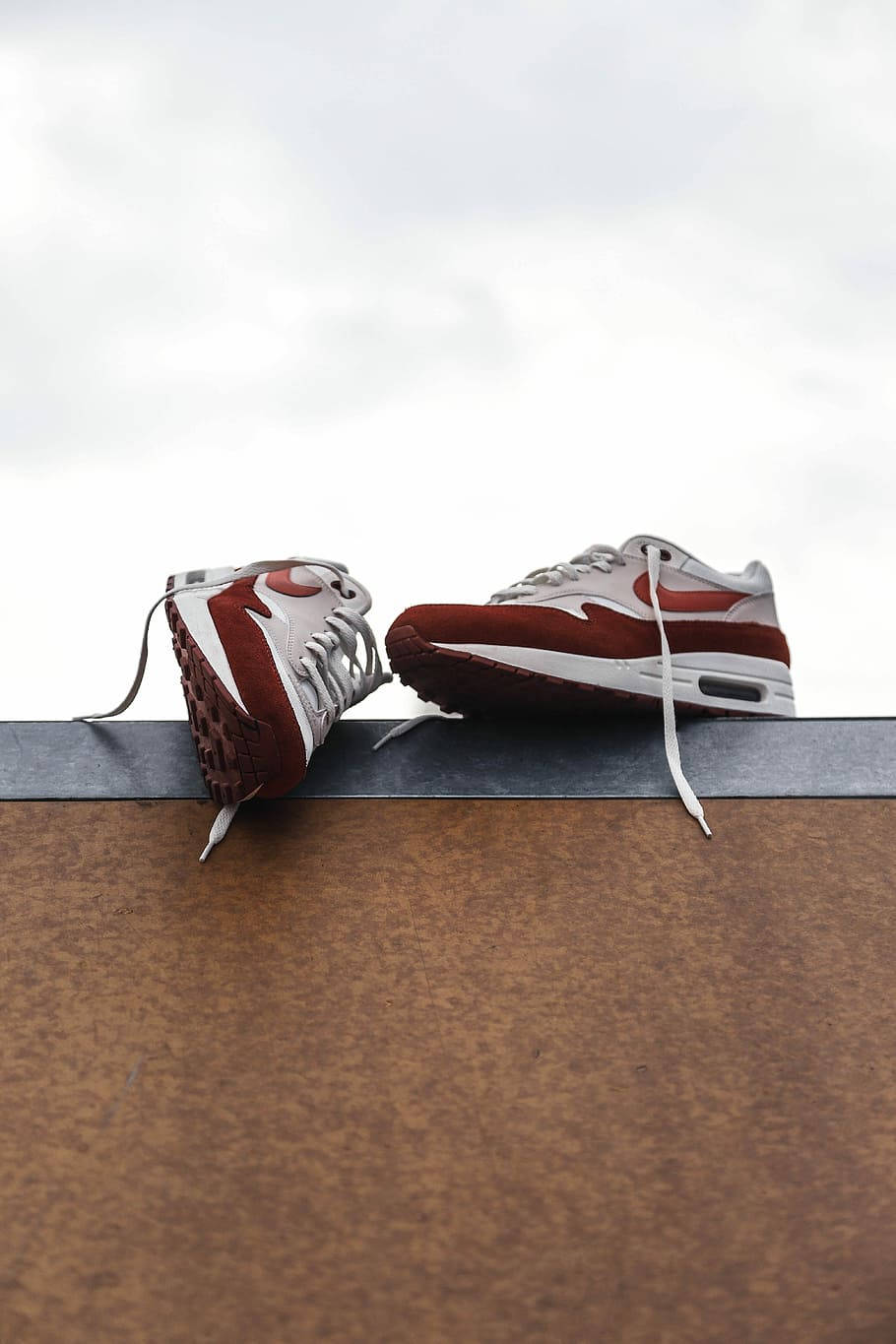 Nike Shoes 桌布 壁紙 — 兩雙紅白運動鞋隨意地放在生鏽的金屬架上，背景是陰天。
