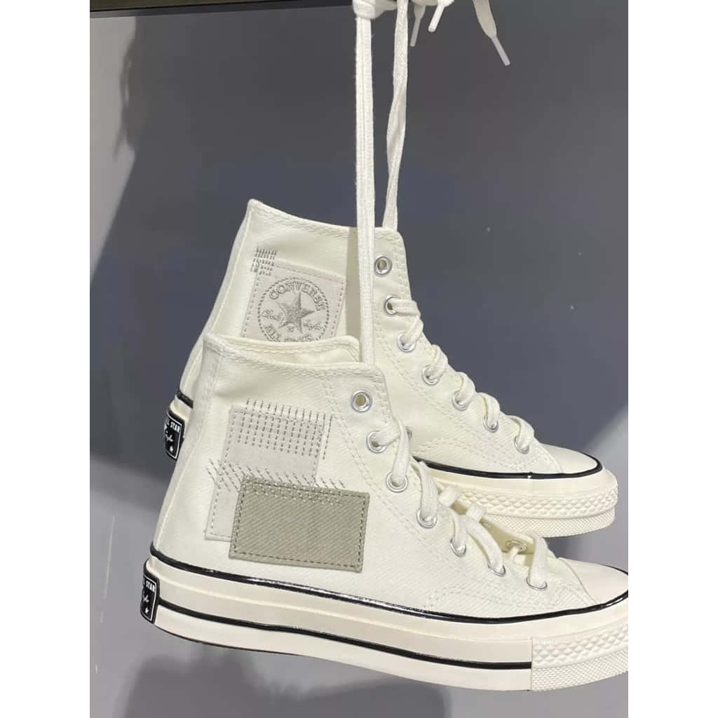 Converse 桌布 壁紙 — 兩雙純白高筒Converse運動鞋懸掛在柔和的灰色背景上，展示細緻的縫線和經典品牌標誌。