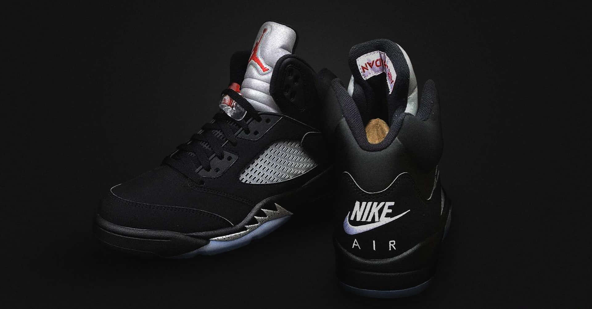 鞋子 桌布 壁紙 — 兩雙黑色Jordan 5運動鞋，帶有銀色和紅色點綴，在深色背景上展示。