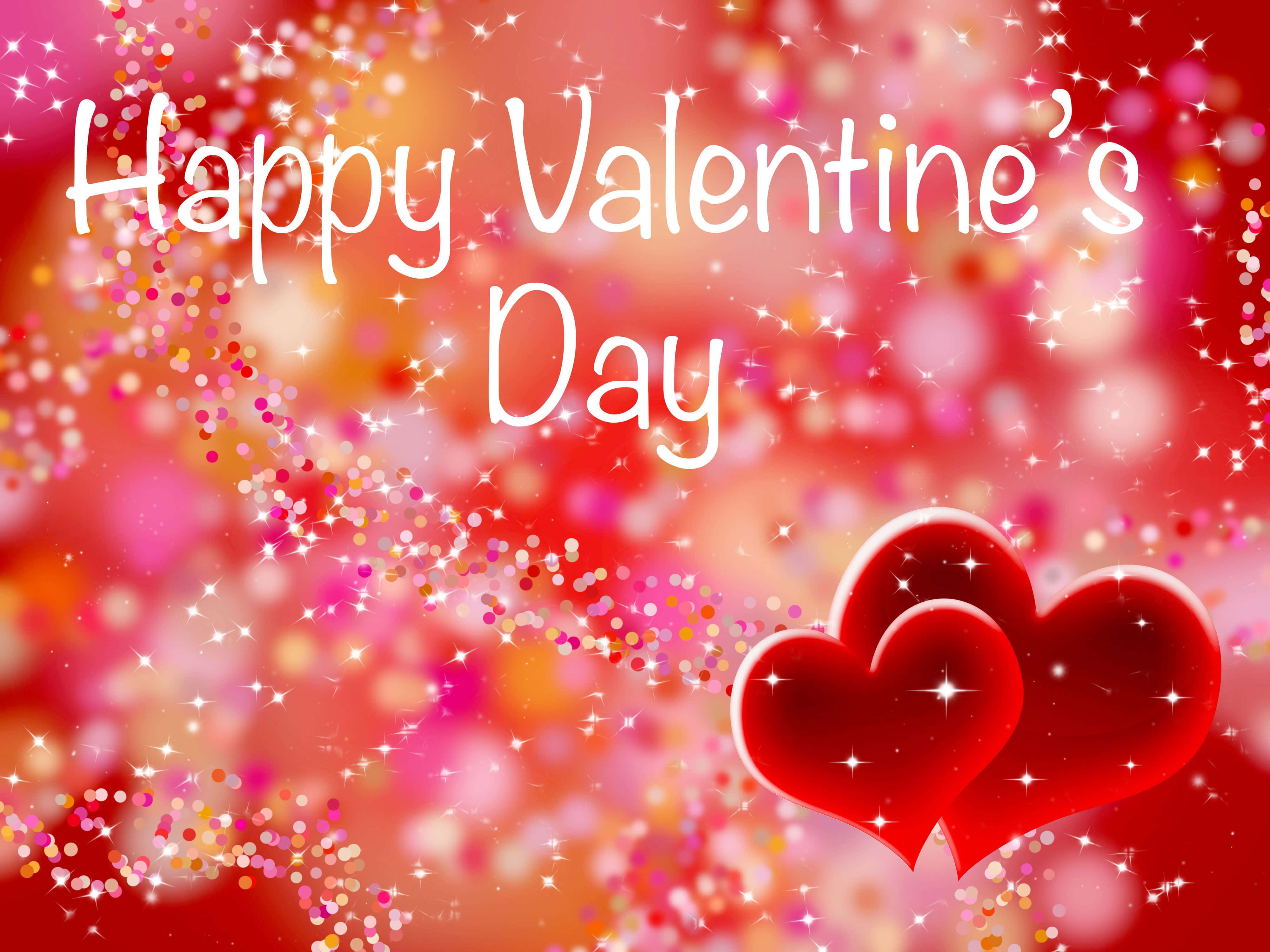 Happy Valentines Day 桌布 壁紙 — 兩顆光滑的紅色心臟在充滿活力的紅粉紅色背景上閃閃發光，帶有閃閃發光的五彩紙屑和「Happy Valentine's Day」文字。