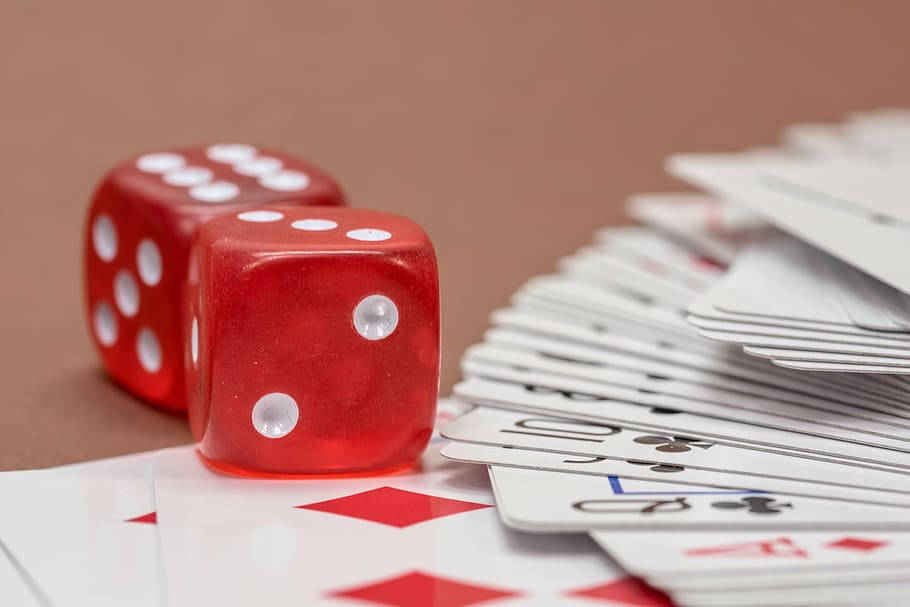 Dice 桌布 壁紙 — 兩顆半透明的紅色骰子放在散落的撲克牌上，背景是溫暖的棕色。