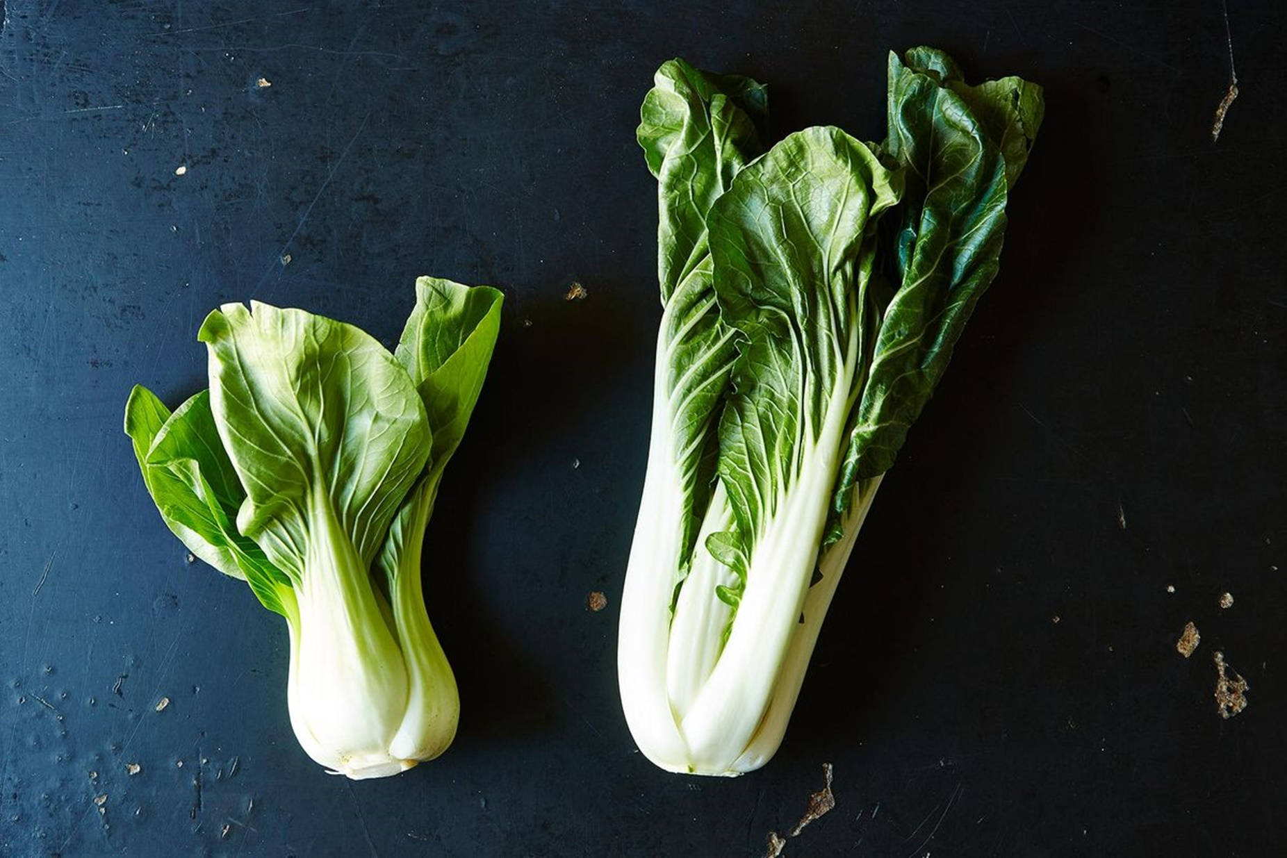 Vegetables 桌布 壁紙 — 兩顆新鮮的小白菜，帶有爽脆的白色莖和鮮綠色的葉子，放在深色紋理表面上。
