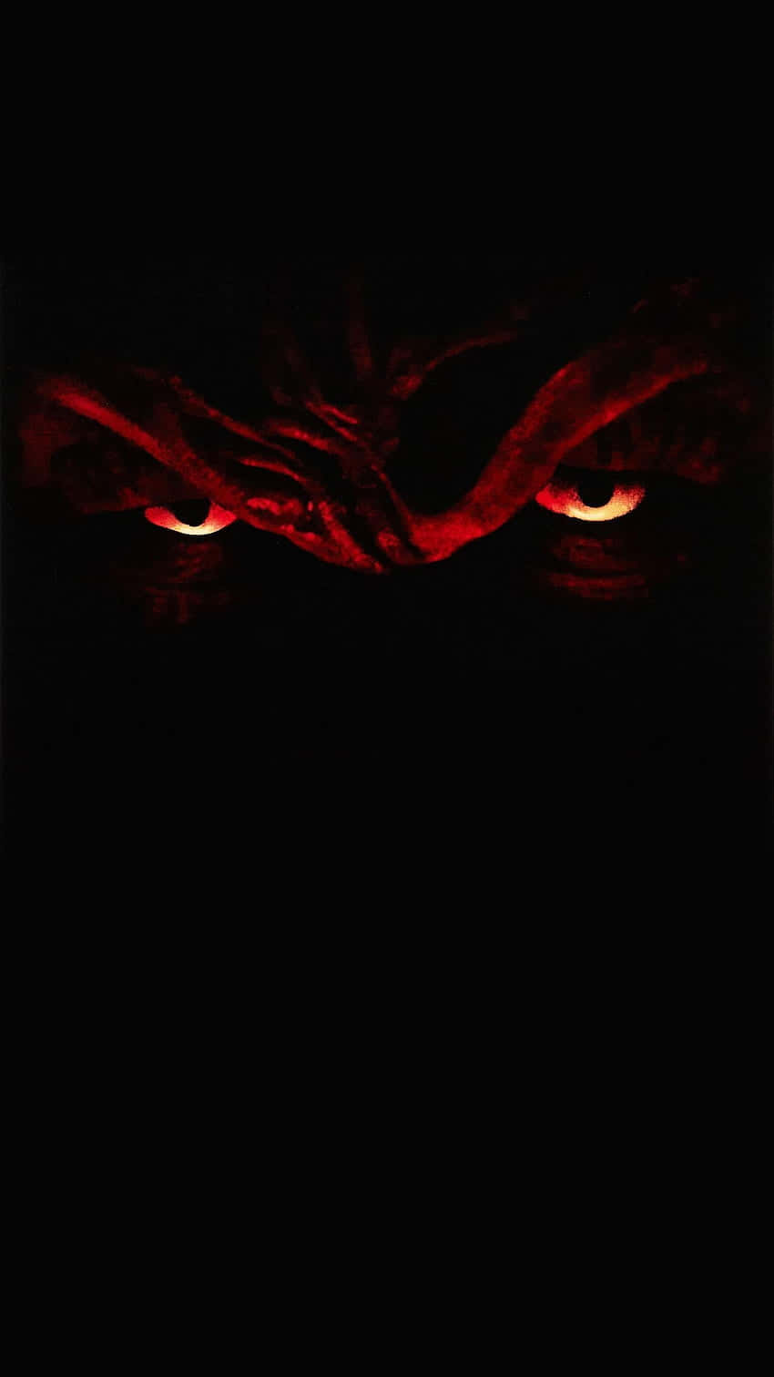 Horror Icons 桌布 壁紙 — 兩顆發光的紅色眼睛從完全的黑暗中凝視，揭示了一個威脅性的看不見的生物。