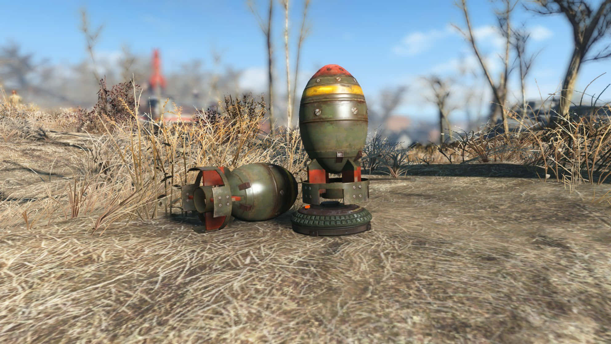 Fallout Nuke 桌布 壁紙 — 兩顆風化的核彈在末日後的荒原上，躺在乾草中，頭頂是清澈的藍天。