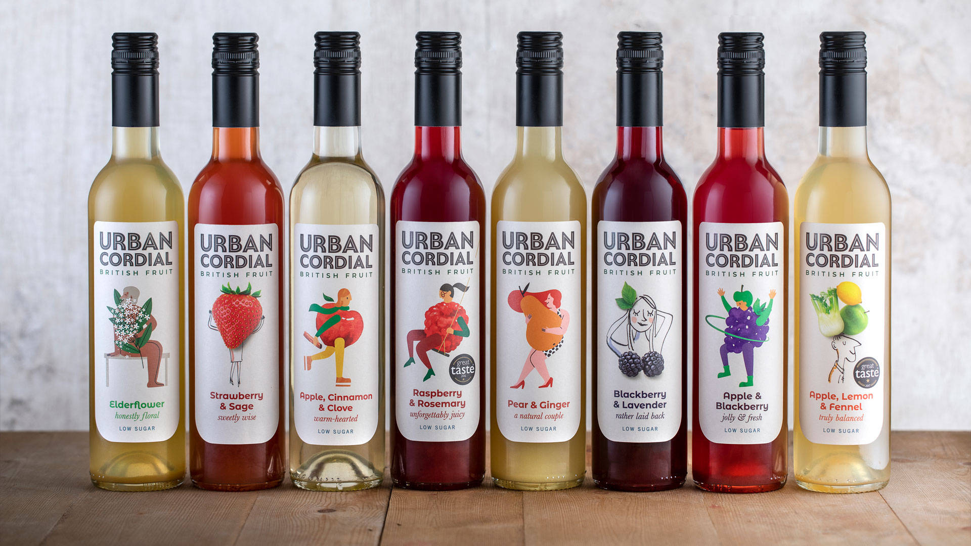 桌布 壁紙 — 八個色彩繽紛的 Urban Cordial 瓶子，帶有插圖水果標籤，整齊地排列在木質表面上。