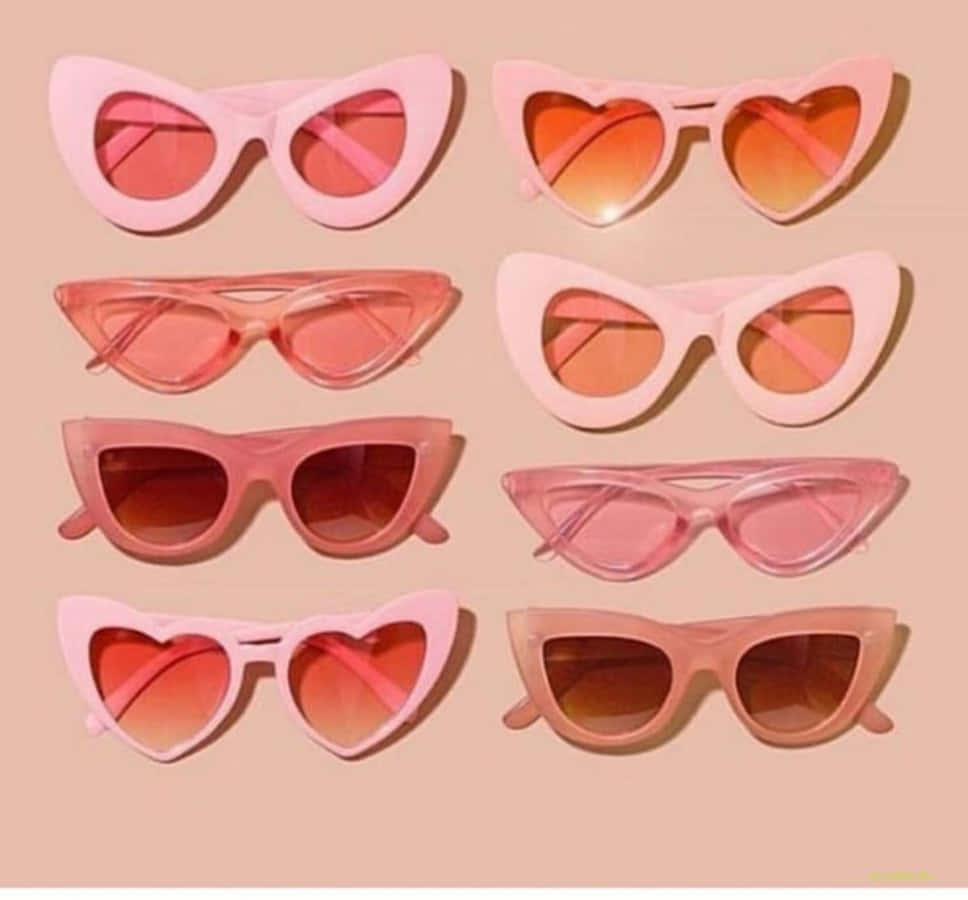 Sunglasses 桌布 壁紙 — 八副復古粉紅色貓眼太陽眼鏡，心形鏡片整齊排列在柔和的蜜桃色背景上。