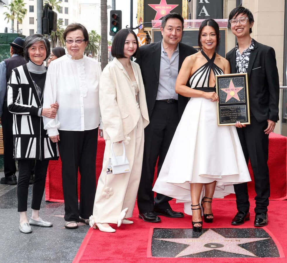 Ming Na Wen 桌布 壁紙 — 六人組在好萊塢星光大道的星星旁紅地毯上擺姿勢，一位身穿白色連衣裙的微笑女士手持牌匾。