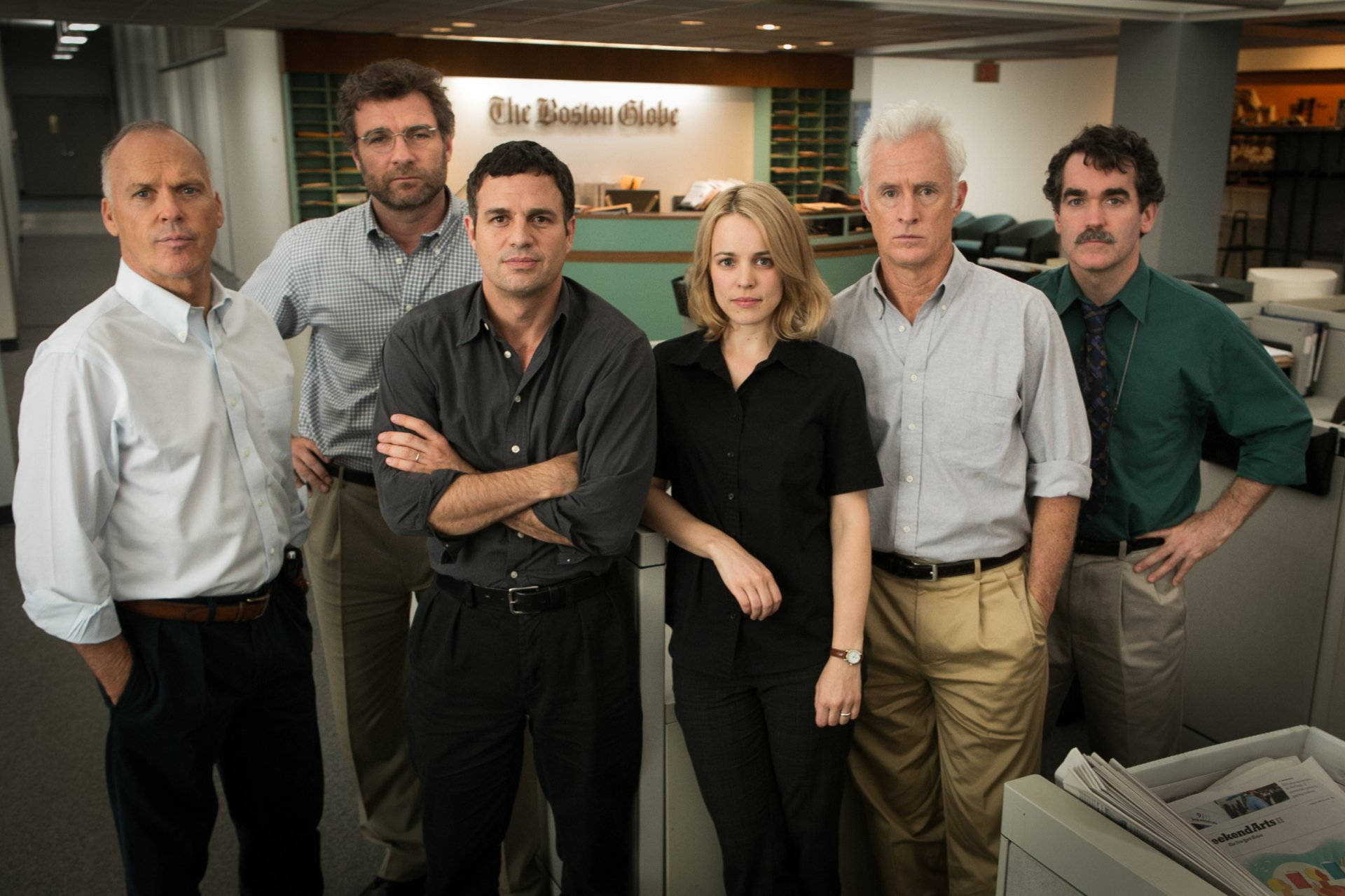 Spotlight 桌布 壁紙 — 六位嚴肅的記者站在新聞編輯室，身後有『The Boston Globe』標誌。