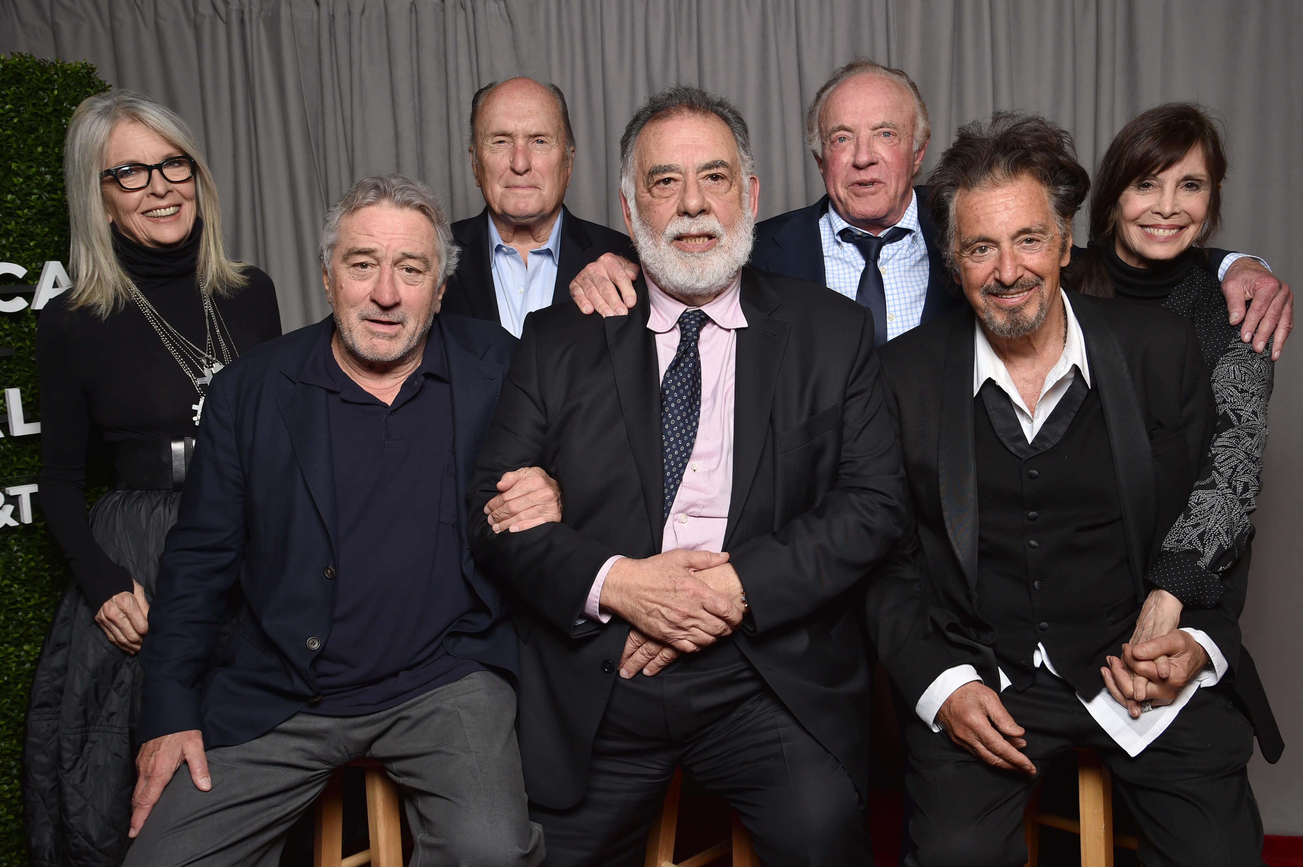 The Godfather 桌布 壁紙 — 六位微笑的名人一起坐在凳子上，以灰色窗簾背景為襯托，在活動中合影。