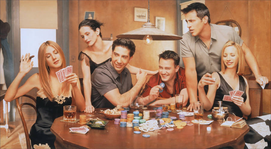 Poker 桌布 壁紙 — 六位朋友聚集在一張木桌旁，身處燈光溫暖的公寓中，笑著用色彩繽紛的籌碼和紙牌玩撲克。