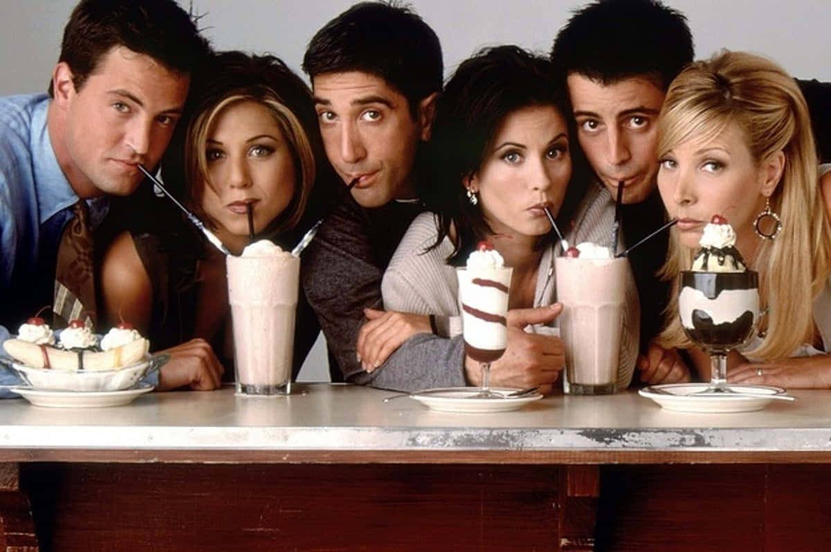 Friends Tv Show 桌布 壁紙 — 六位朋友靠在餐廳櫃檯上，喝著奶昔，吃著聖代，表情俏皮。