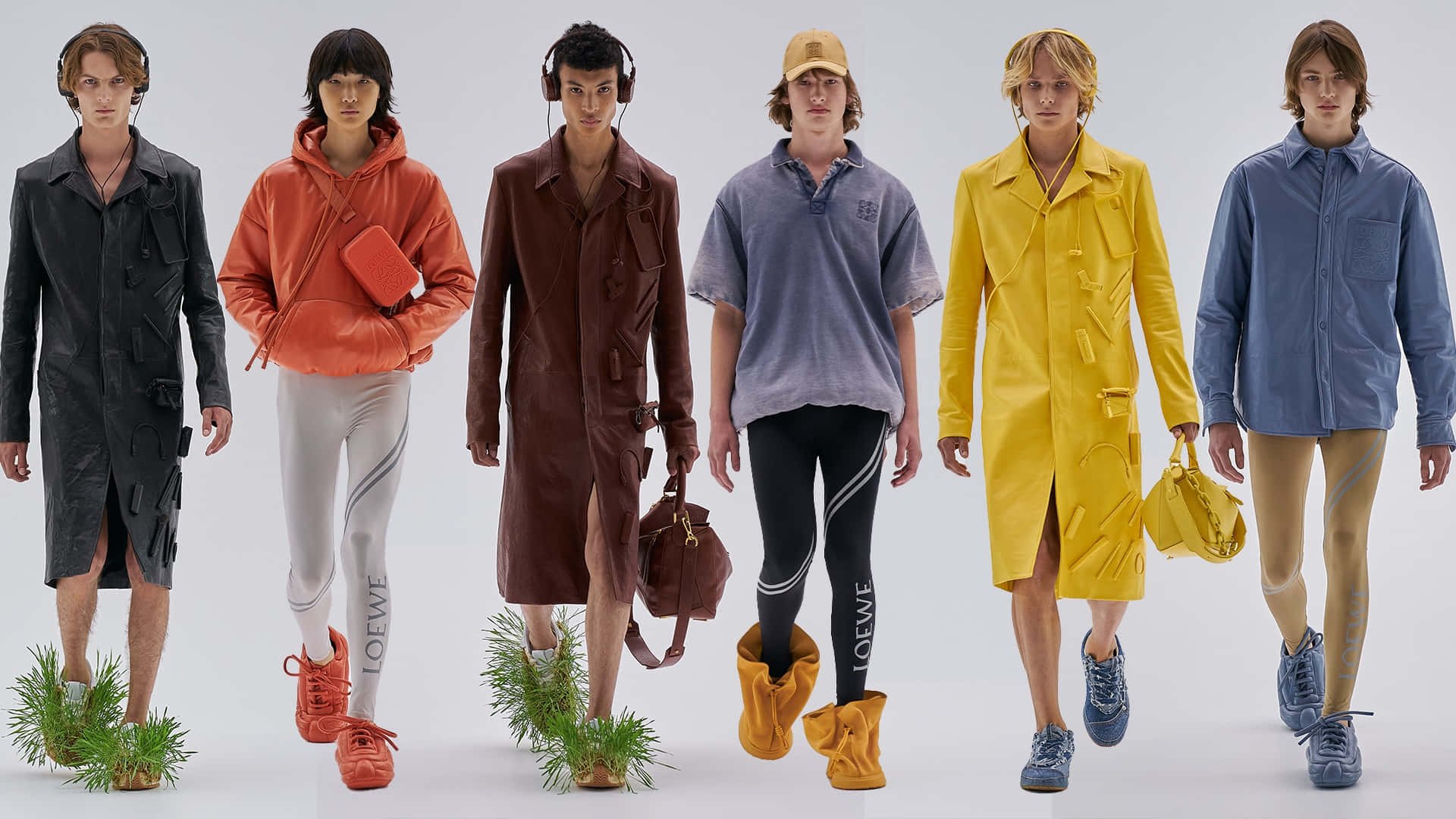 Mens Fashion 桌布 壁紙 — 六位模特兒穿著色彩繽紛的時裝，在白色攝影棚地板上行走，腳邊有草叢。