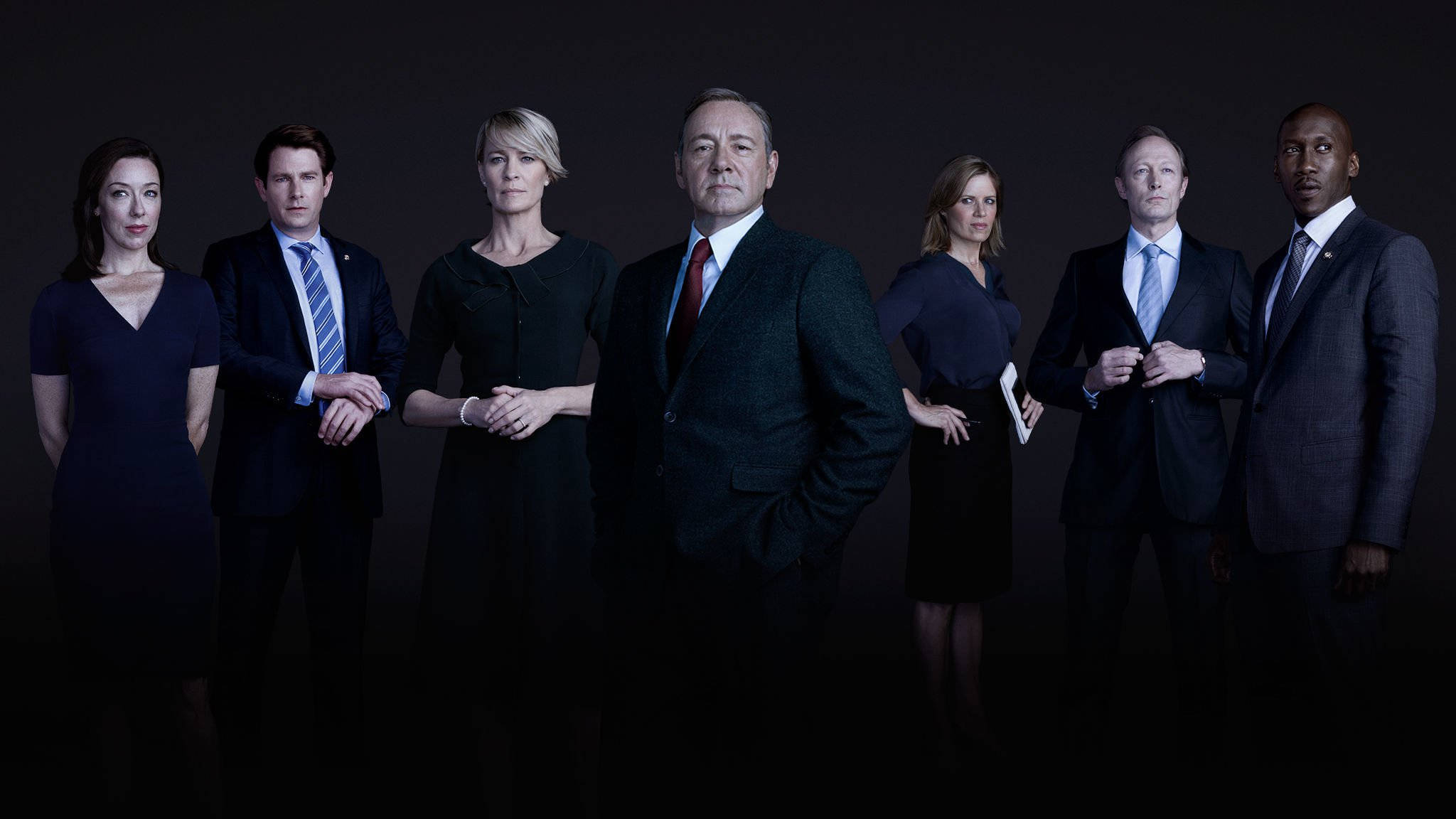 kevin spacey 桌布 壁紙 — 六位穿著正式服裝的人士站在昏暗的攝影棚中，表情嚴肅，燈光效果戲劇化。