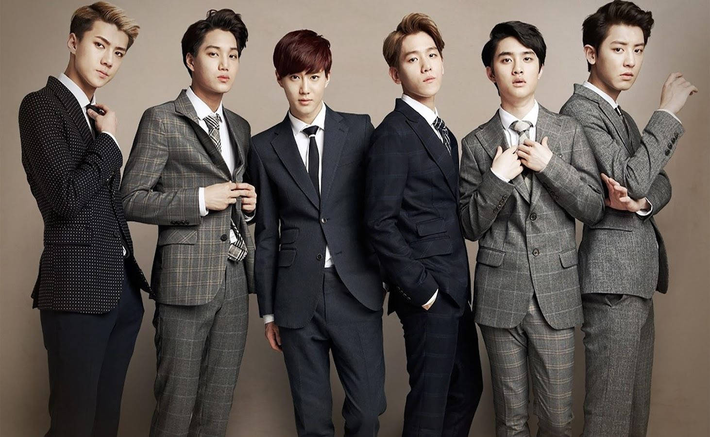K-pop 桌布 壁紙 — 六位穿著訂製西裝的時尚年輕男性，在簡約的攝影棚背景下自信地擺出嚴肅的表情。