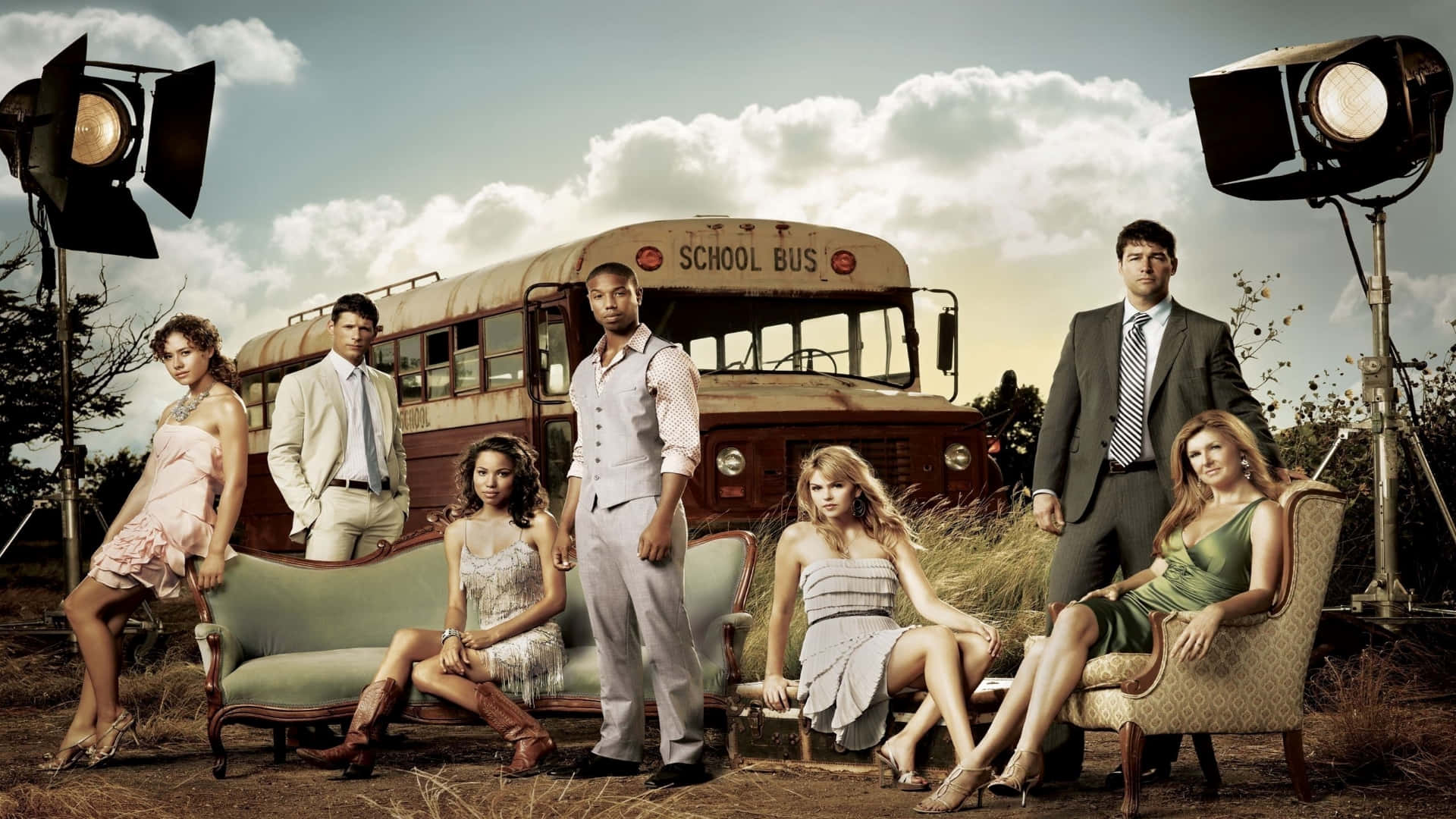 Tv Series 桌布 壁紙 — 六位衣著優雅的人在田野的攝影棚燈光下，圍繞著復古家具和一輛生鏽的校車戲劇性地擺姿勢。