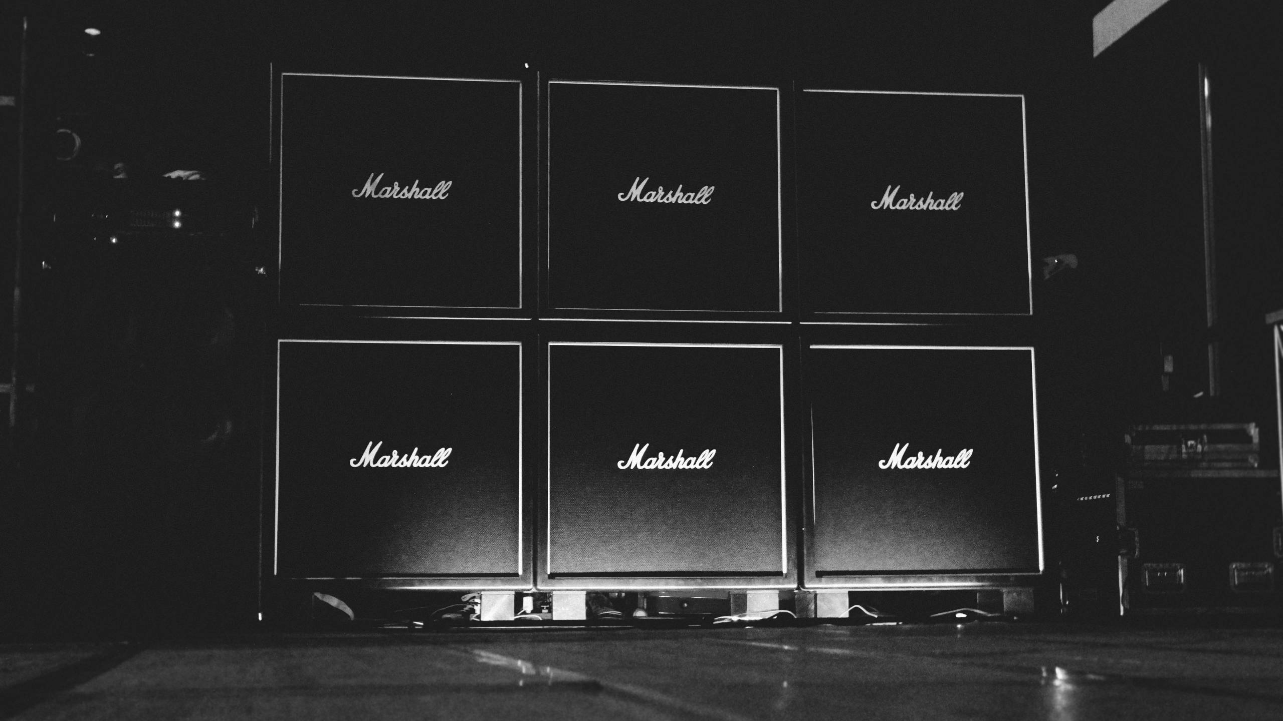 Marshall 桌布 壁紙 — 六個Marshall吉他擴音器以網格排列，在黑暗舞台背景下發出白色文字光芒。