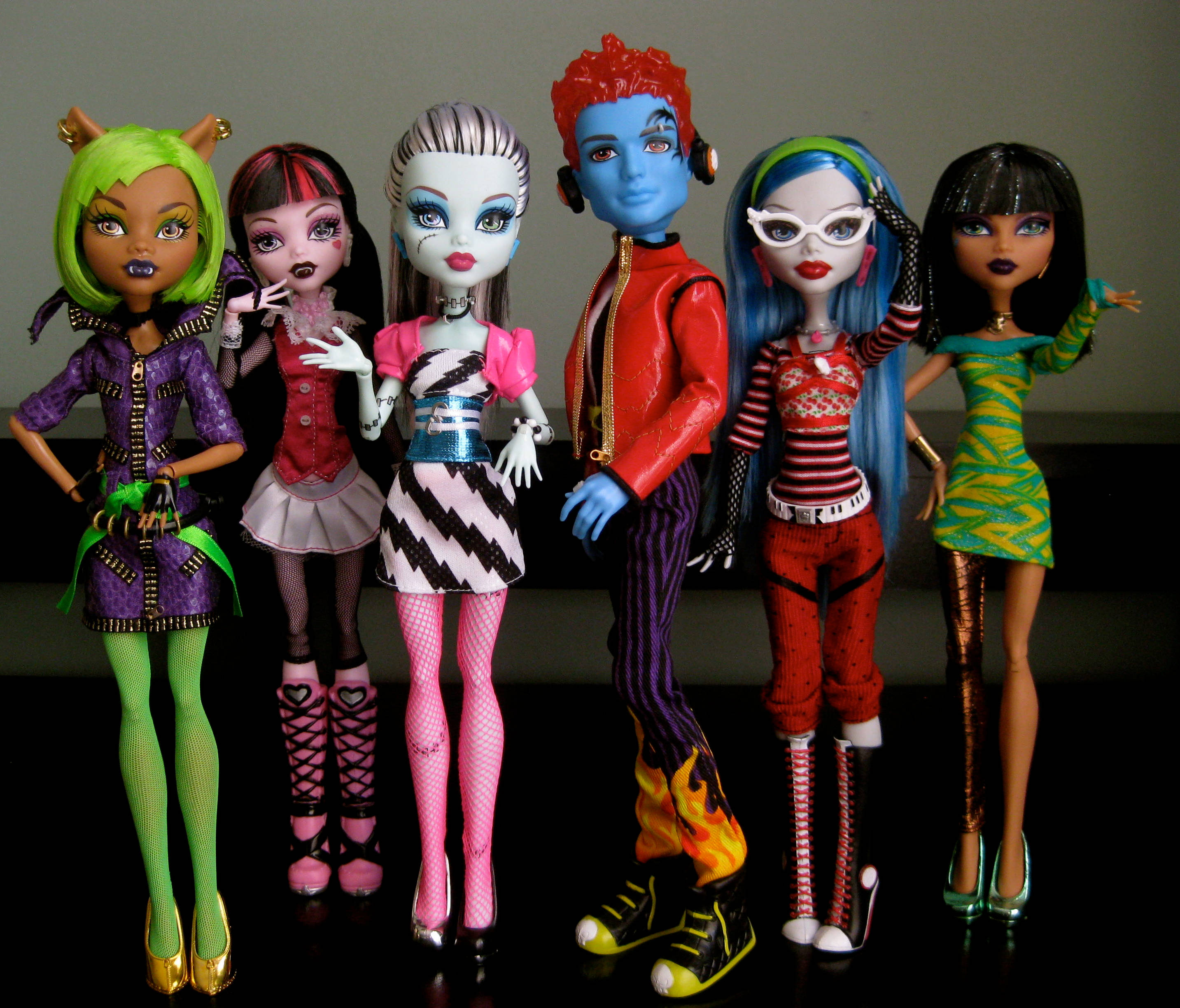 bratz 美學 桌布 壁紙 — 六個Monster High公仔擁有色彩繽紛的頭髮和龐克時尚，在純灰色牆壁前自信地擺姿勢。