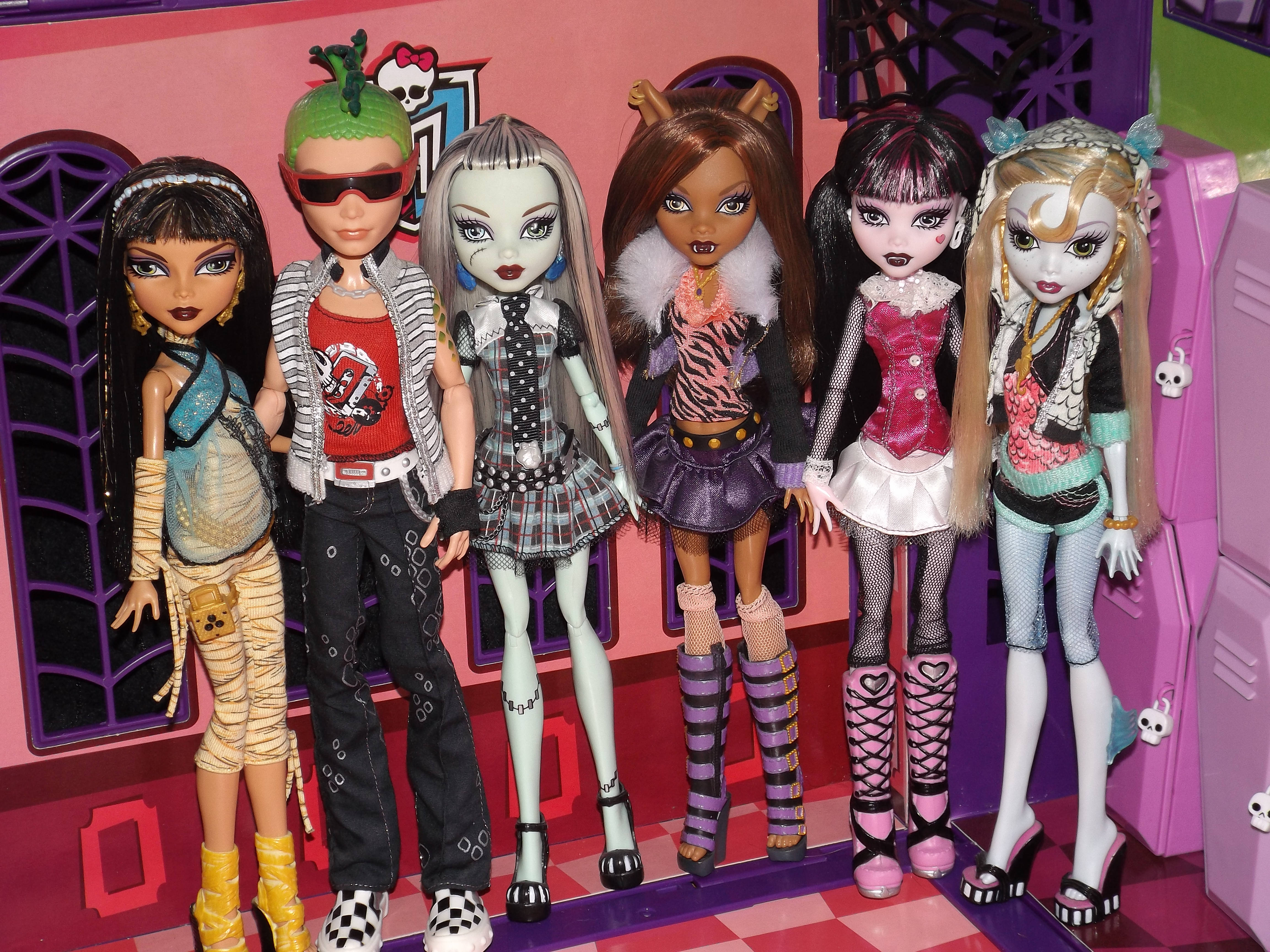 bratz 美學 桌布 壁紙 — 六個Monster High公仔穿著哥德龐克服裝，在粉紅色更衣室背景前擺姿勢，背景有蜘蛛網窗戶。