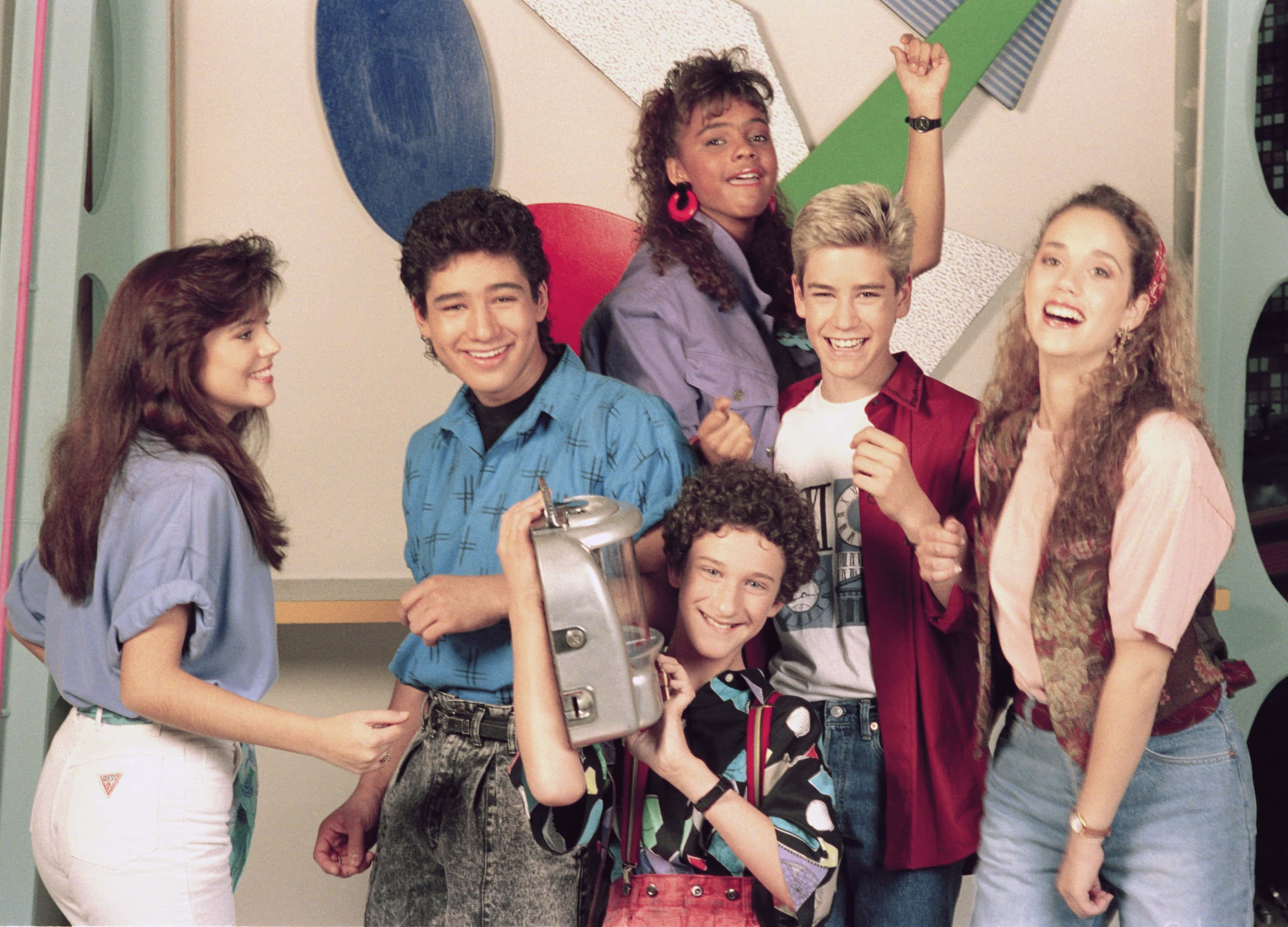 Mark-paul Gosselaar 桌布 壁紙 — 六個微笑的90年代青少年在色彩繽紛的幾何工作室中愉快地擺姿勢，其中一人拿著銀色手提音響。