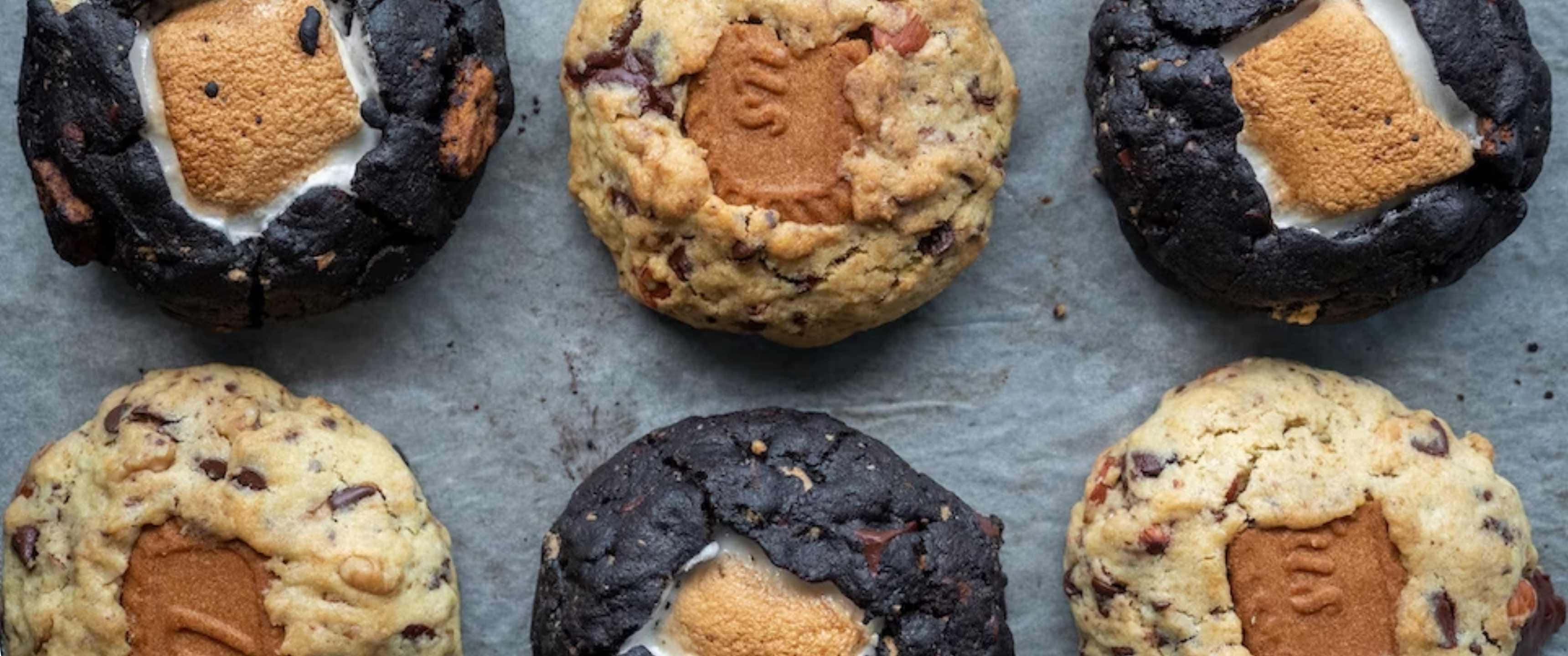 Cookies 桌布 壁紙 — 六個新鮮出爐的巧克力餅乾，內有烤棉花糖夾心，放在鋪有烘焙紙的烤盤上。
