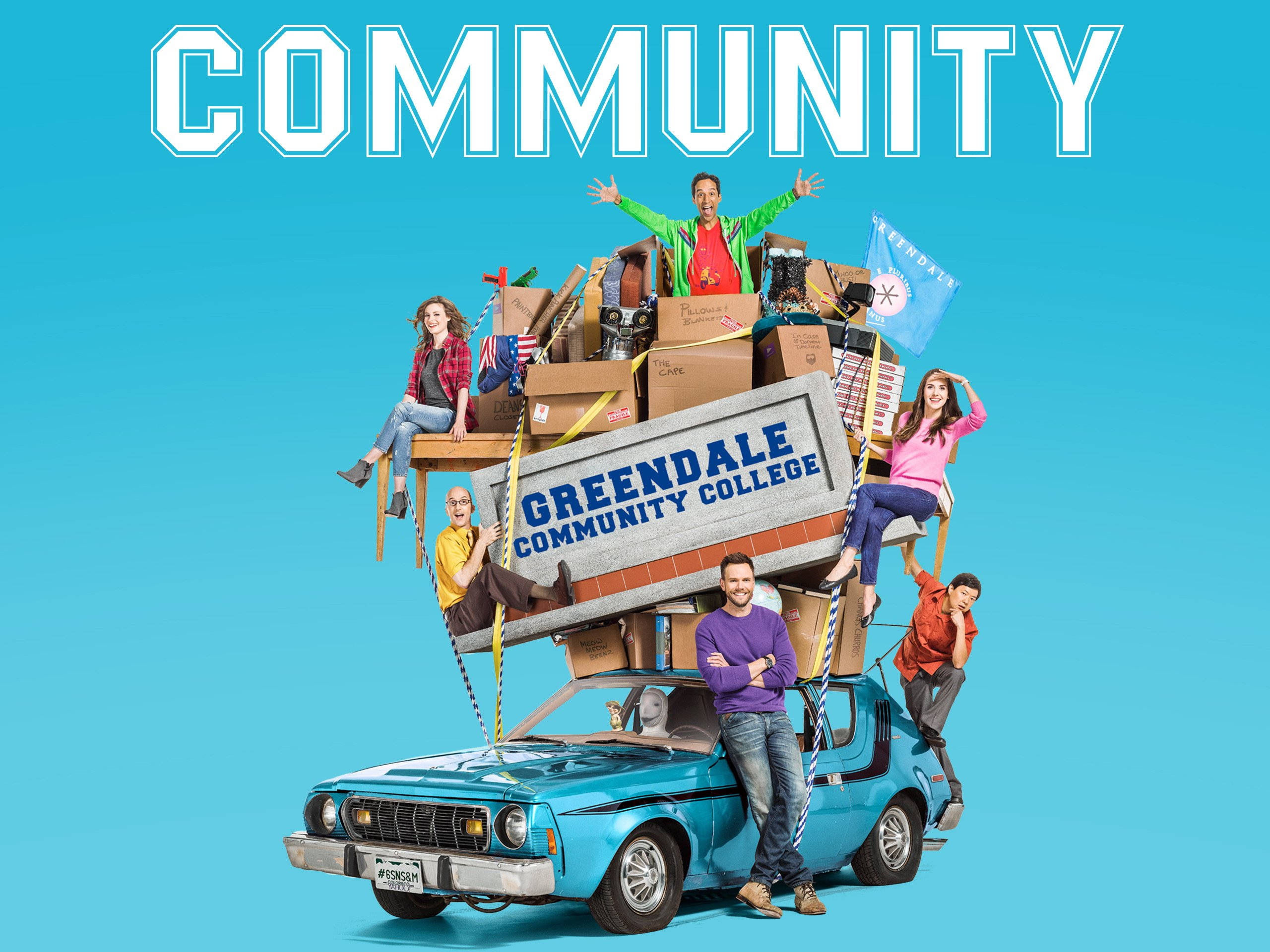 Community 桌布 壁紙 — 六個朋友擠在一輛藍色汽車上，車上堆滿了盒子和一個 Greendale Community College 標誌，背景是明亮的藍色。