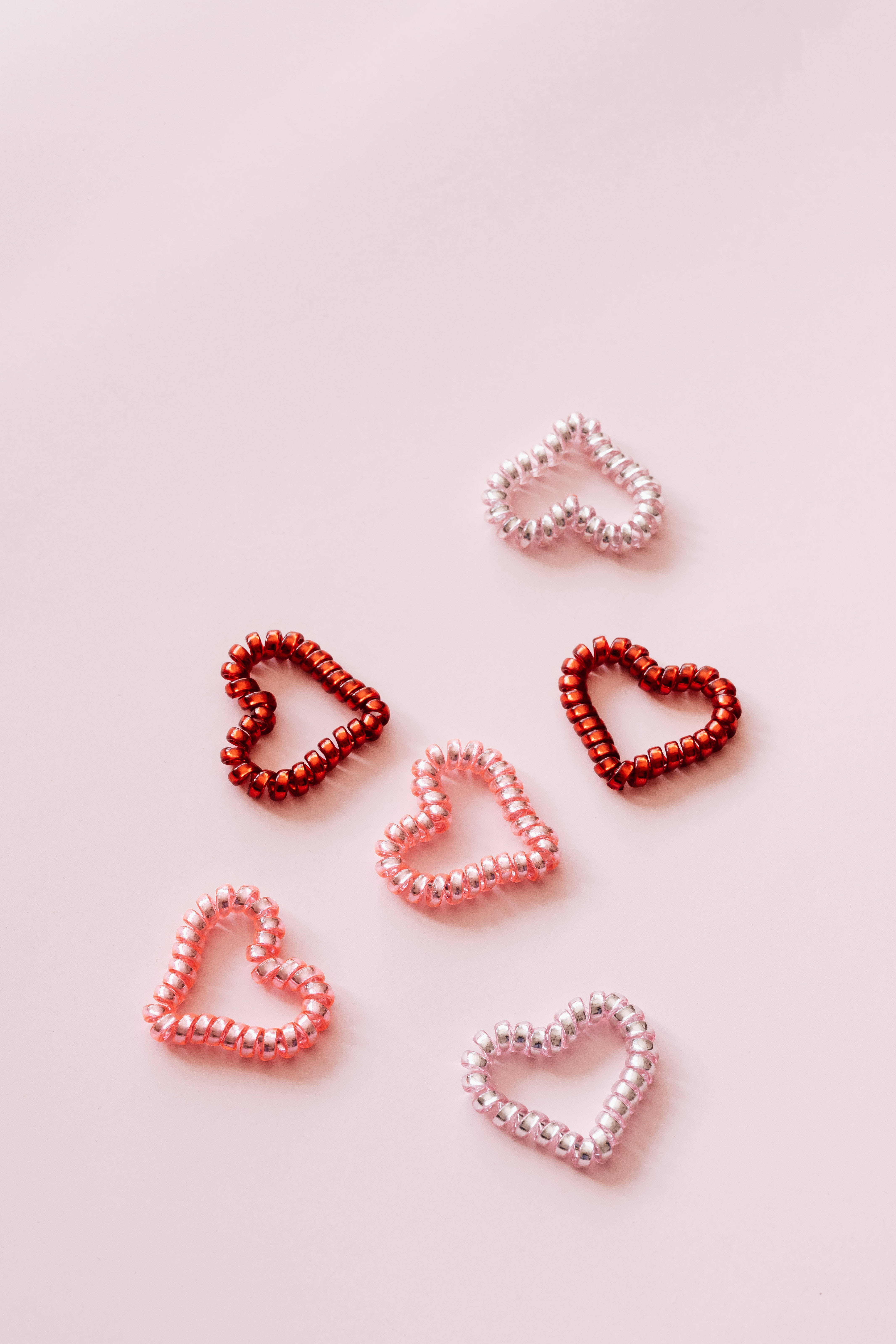 Pastel Pink Heart 桌布 壁紙 — 六個紅色、粉紅色和銀色的串珠心形圖案，放置在柔和的腮紅背景上。