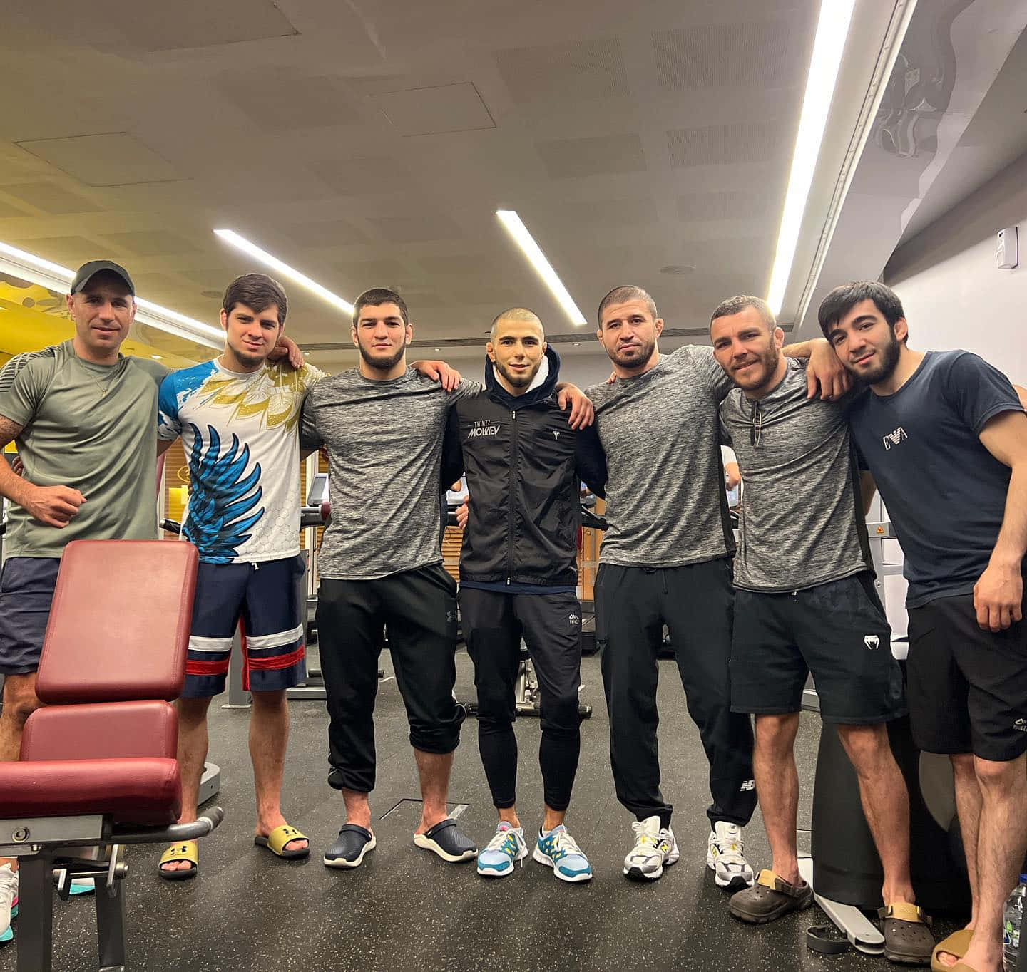 UFC 桌布 壁紙 — 六個肌肉發達的男人穿著健身服裝，在光線明亮的健身中心互相搭肩合照。