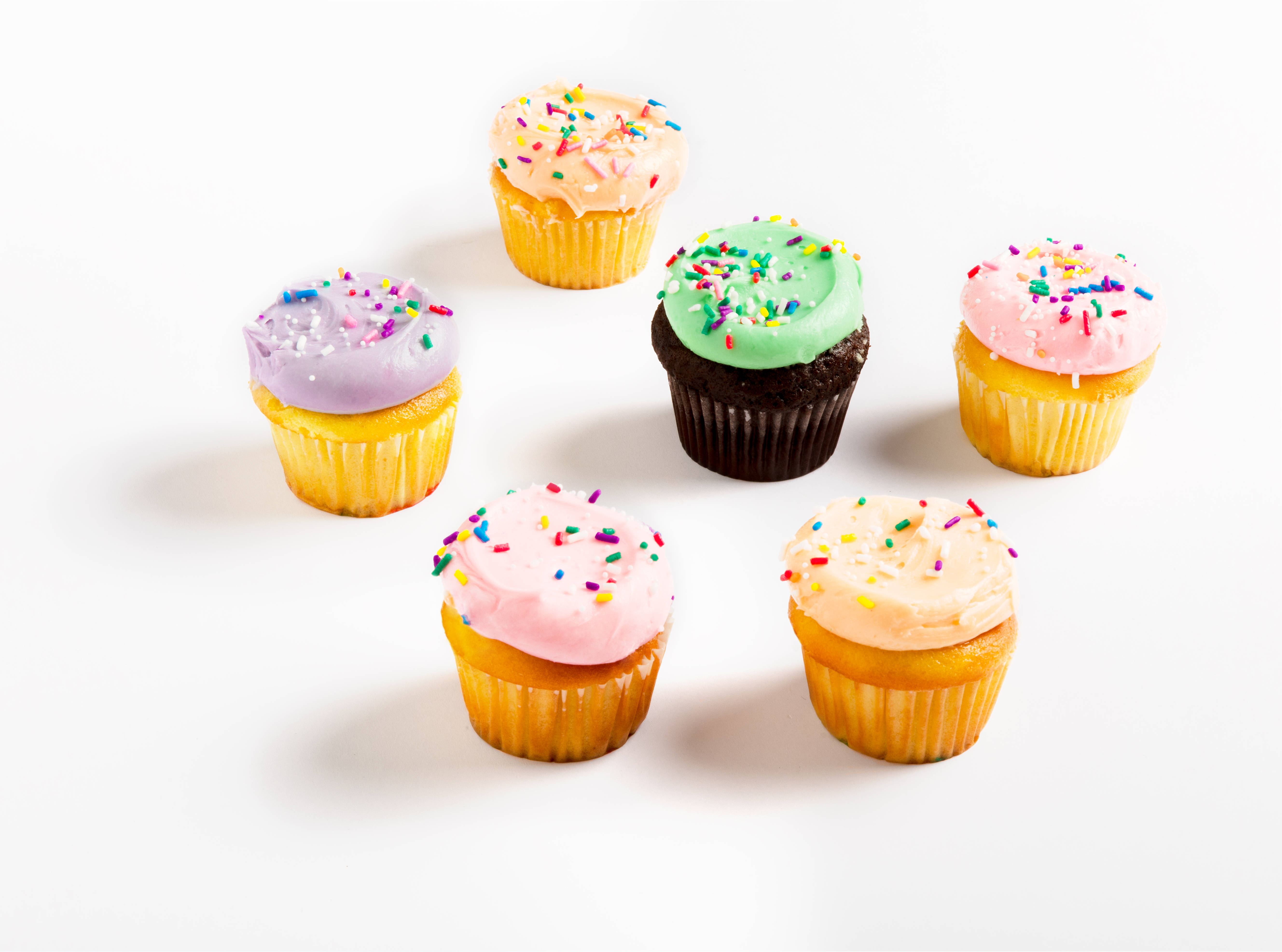 Cupcake 桌布 壁紙 — 六個色彩繽紛的杯子蛋糕，帶有粉彩色糖霜和彩虹糖針，整齊排列在潔白的背景上。
