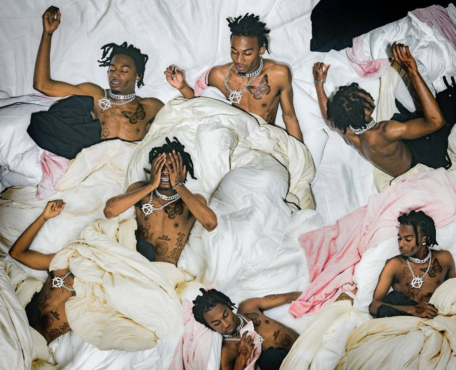 Carti 桌布 壁紙 — 六個赤膊刺青男子戴著鎖鏈，戲劇性地攤在凌亂的白色和粉紅色床單上，構成混亂的臥室場景。