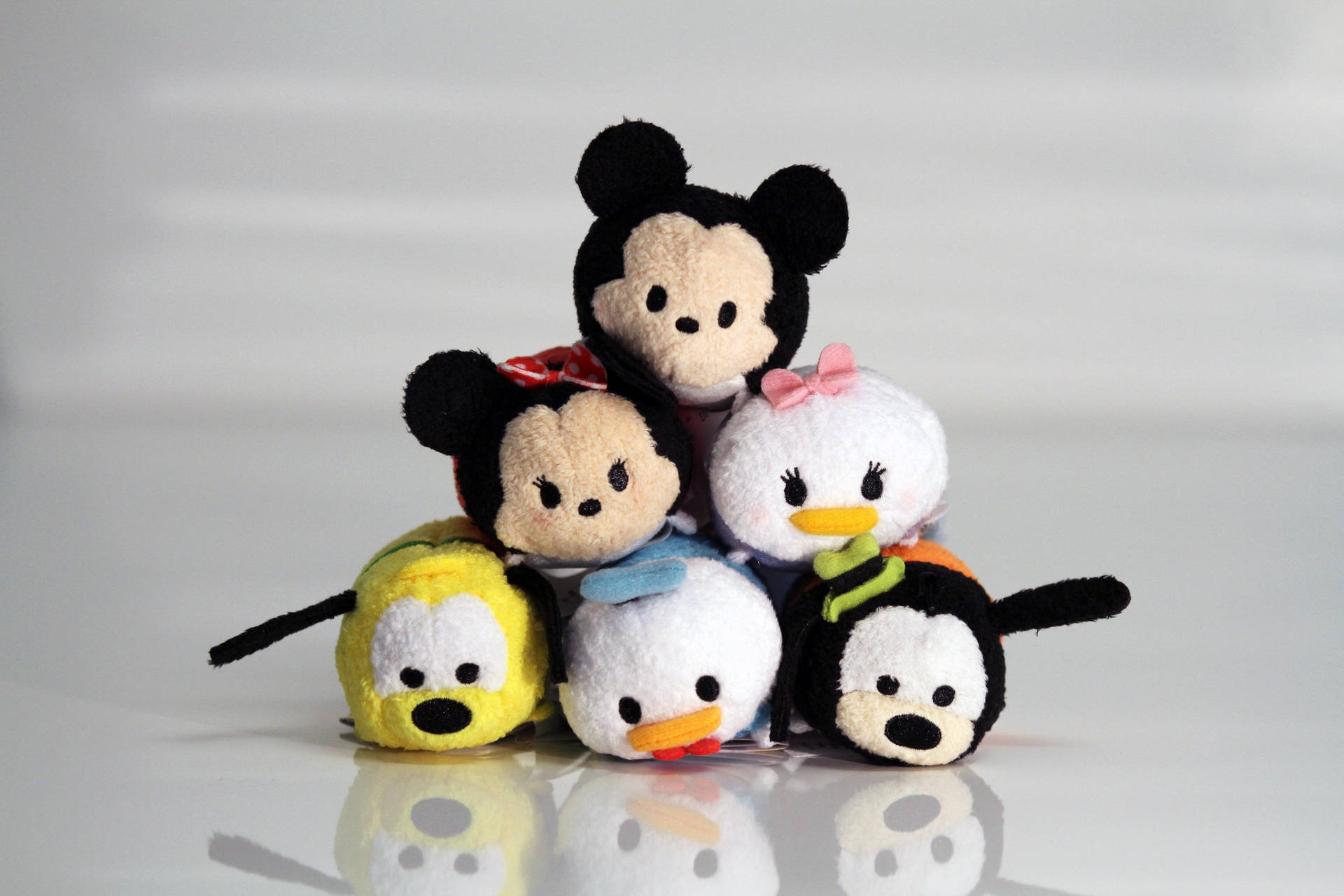 六個迪士尼Tsum Tsum絨毛玩具堆疊在反光的白色表面上。 — Tsum tsum 壁紙