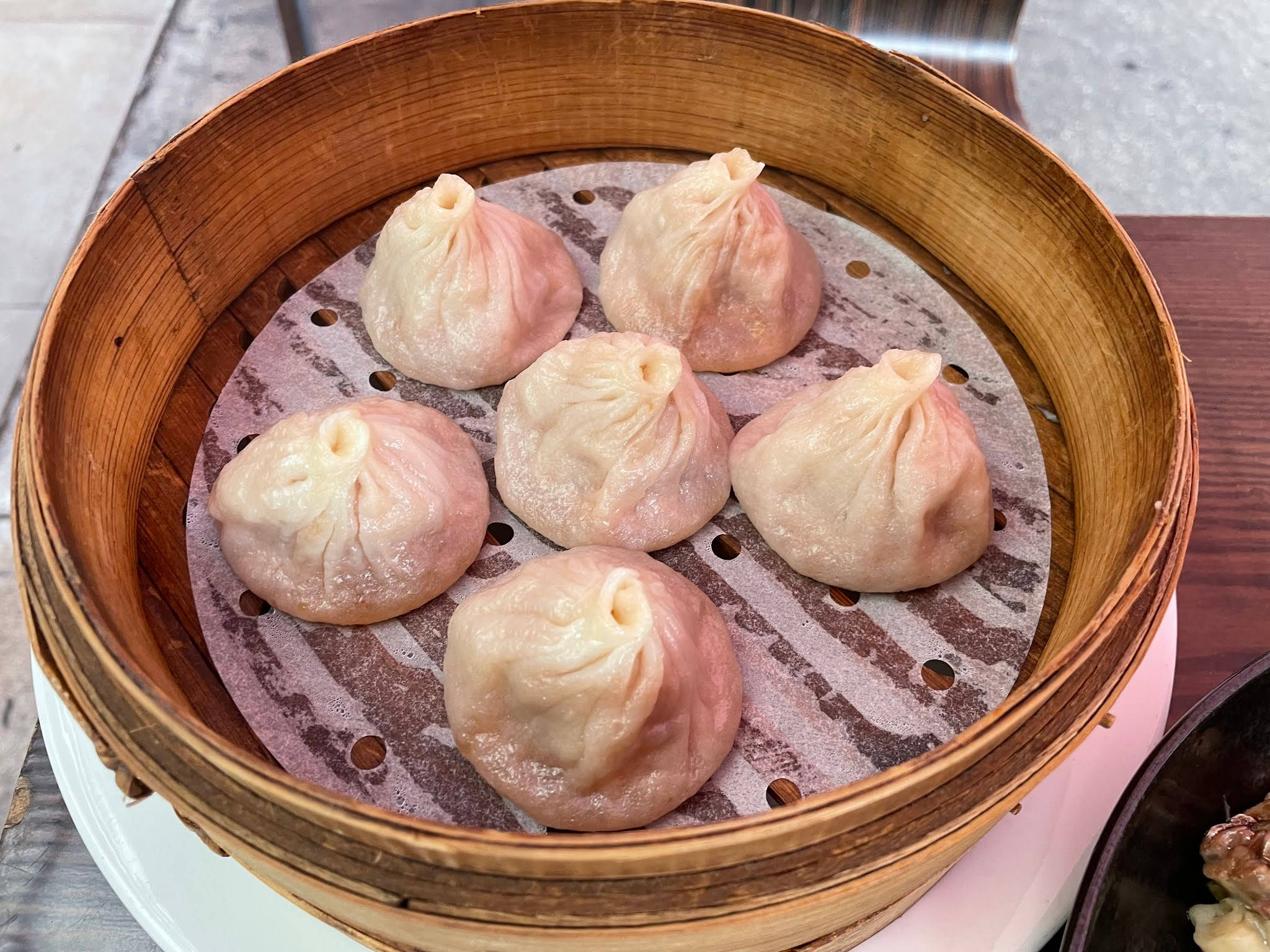 steam 桌布 壁紙 — 六個飽滿多汁的餃子放在竹蒸籠裡，蒸籠有可見的蒸汽孔和木邊。