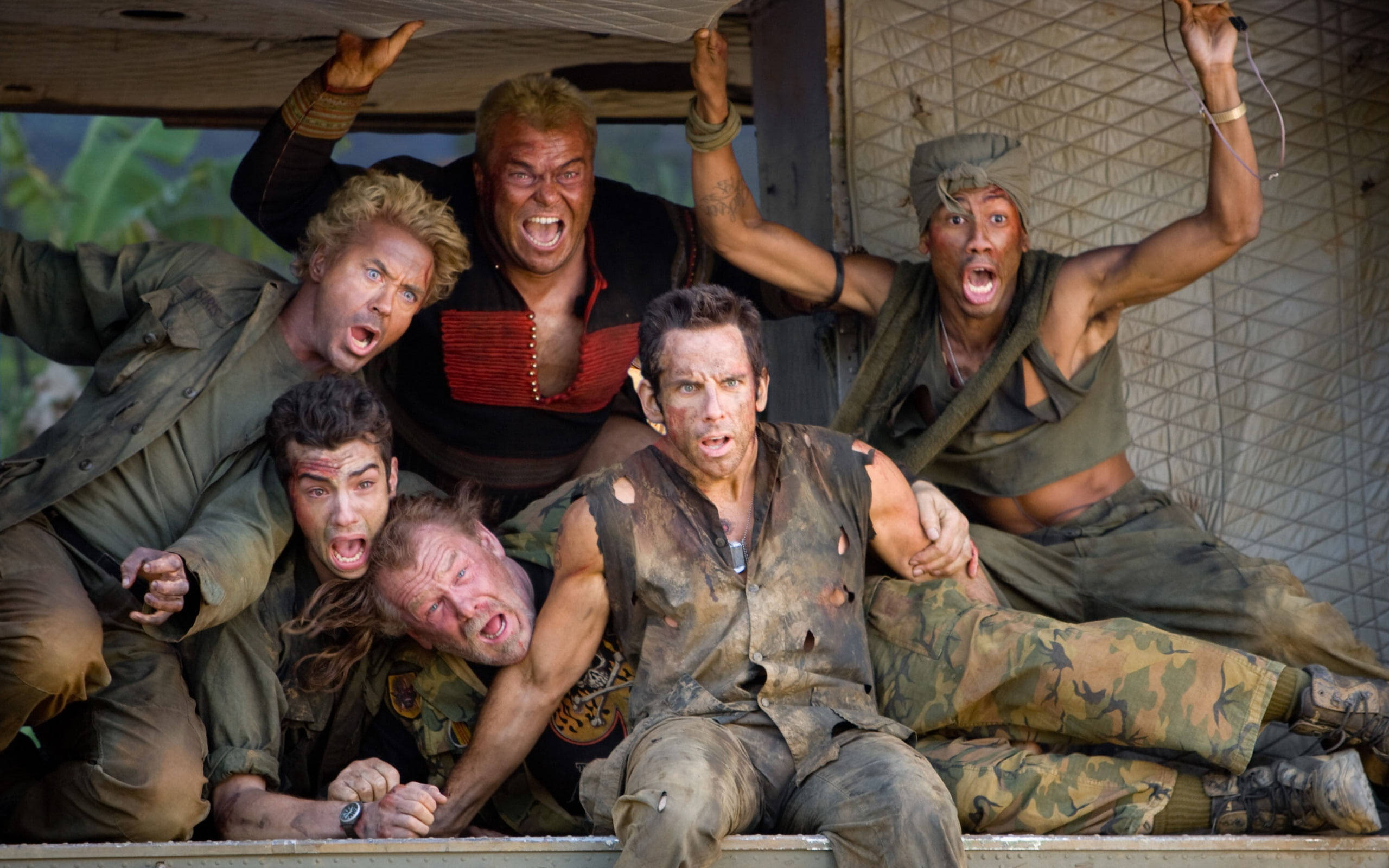 班·史提勒 桌布 壁紙 — 六名滿身泥濘、身穿破爛軍裝的士兵在叢林掩體中瘋狂尖叫，身後是綠色樹葉。