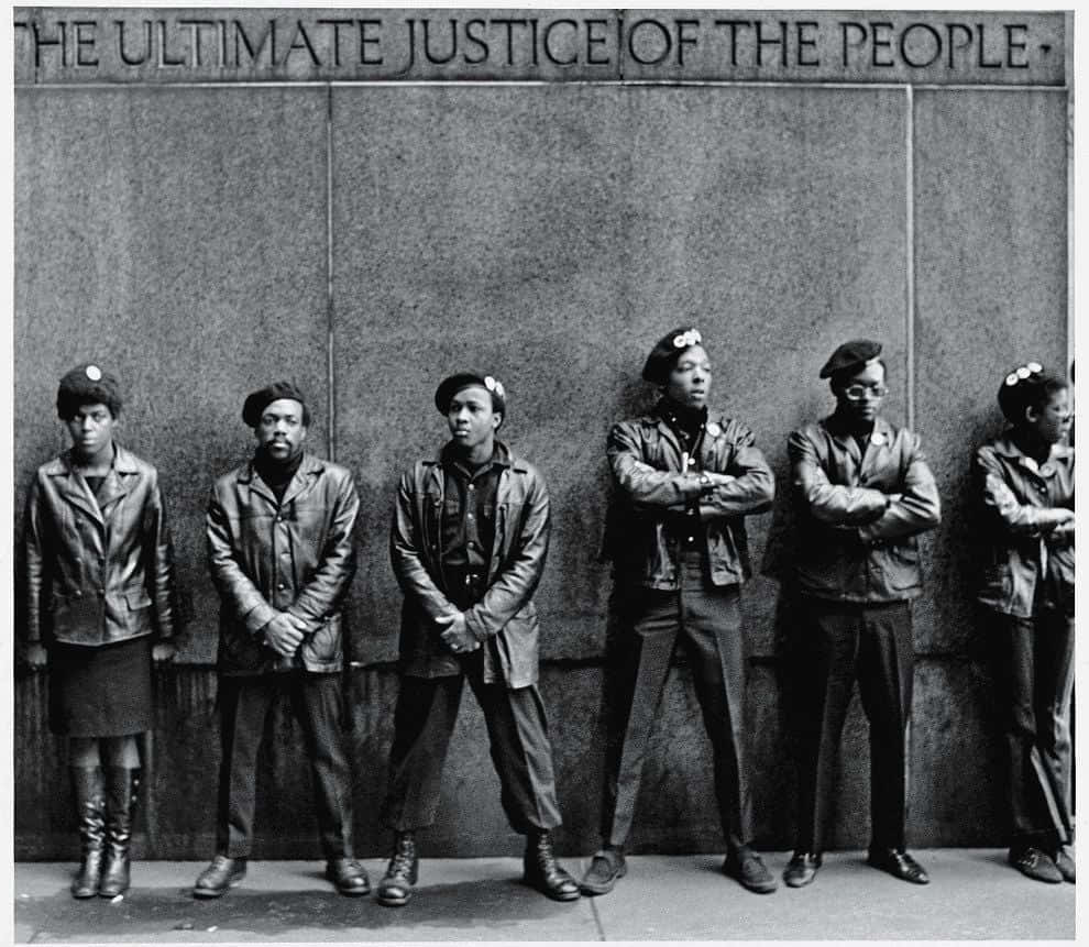 Black Panther Party 桌布 壁紙 — 六名穿著皮夾克和貝雷帽的黑人，莊嚴地站在刻有「THE ULTIMATE JUSTICE OF THE PEOPLE」的混凝土牆前。