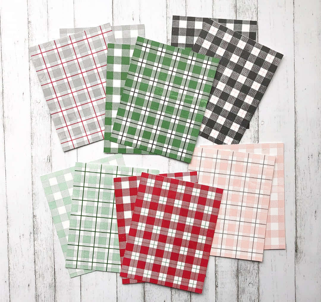 Plaid 桌布 壁紙 — 六塊紅、綠、黑、粉紅色的格子布料樣品，排列在白色風化木質表面上。