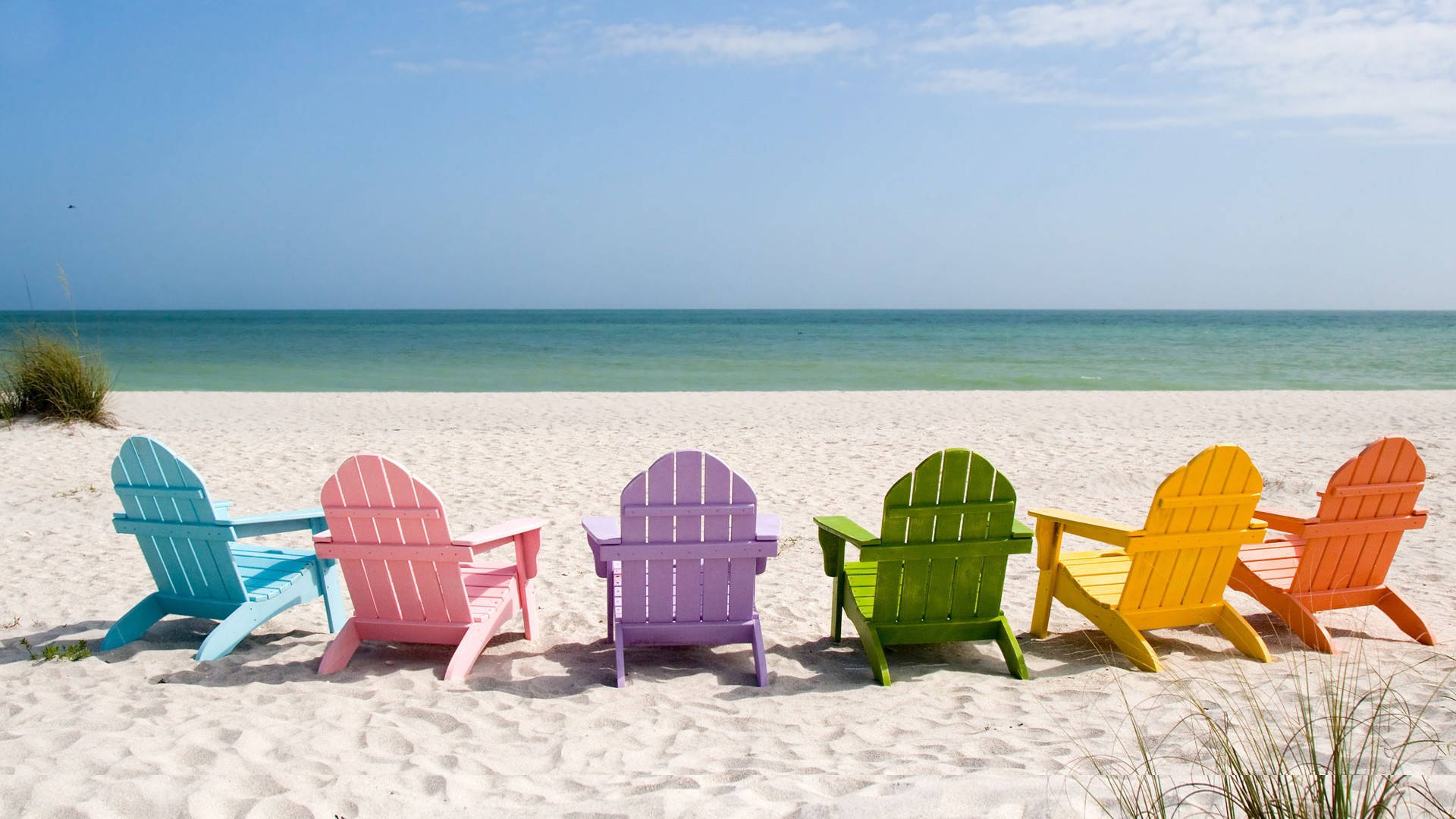 Beach Vacation 桌布 壁紙 — 六張色彩鮮豔的Adirondack椅子面向海洋，在陽光明媚的白色沙灘上，天空湛藍清澈。