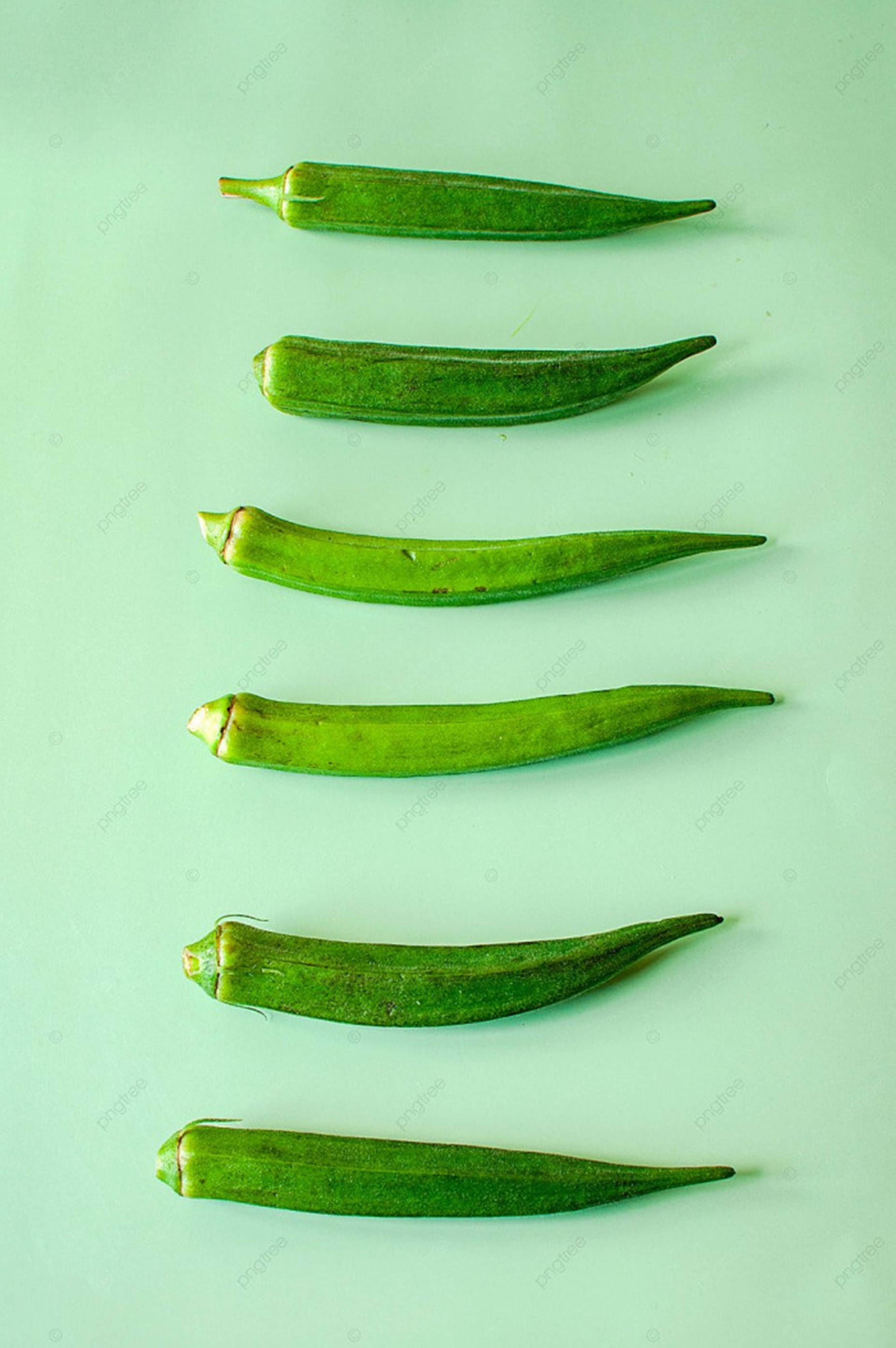 Okra 桌布 壁紙 — 六條新鮮的綠色秋葵莢對角排列在柔和的薄荷色背景上，帶有柔和的陰影。