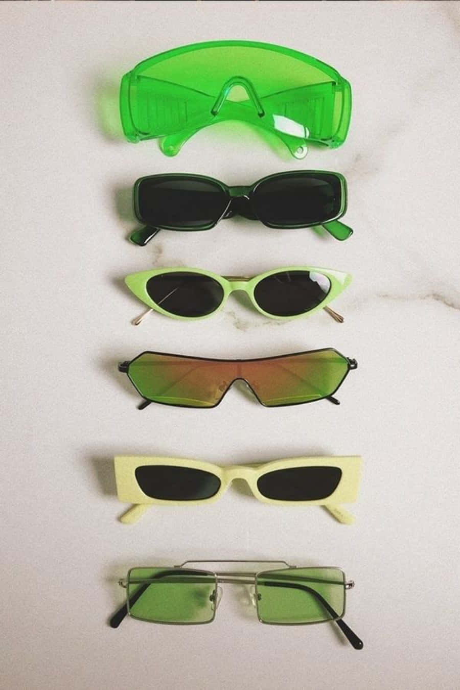 Sunglasses 桌布 壁紙 — 六款時尚太陽眼鏡，呈現不同綠色調和形狀，整齊排列在白色大理石表面上。