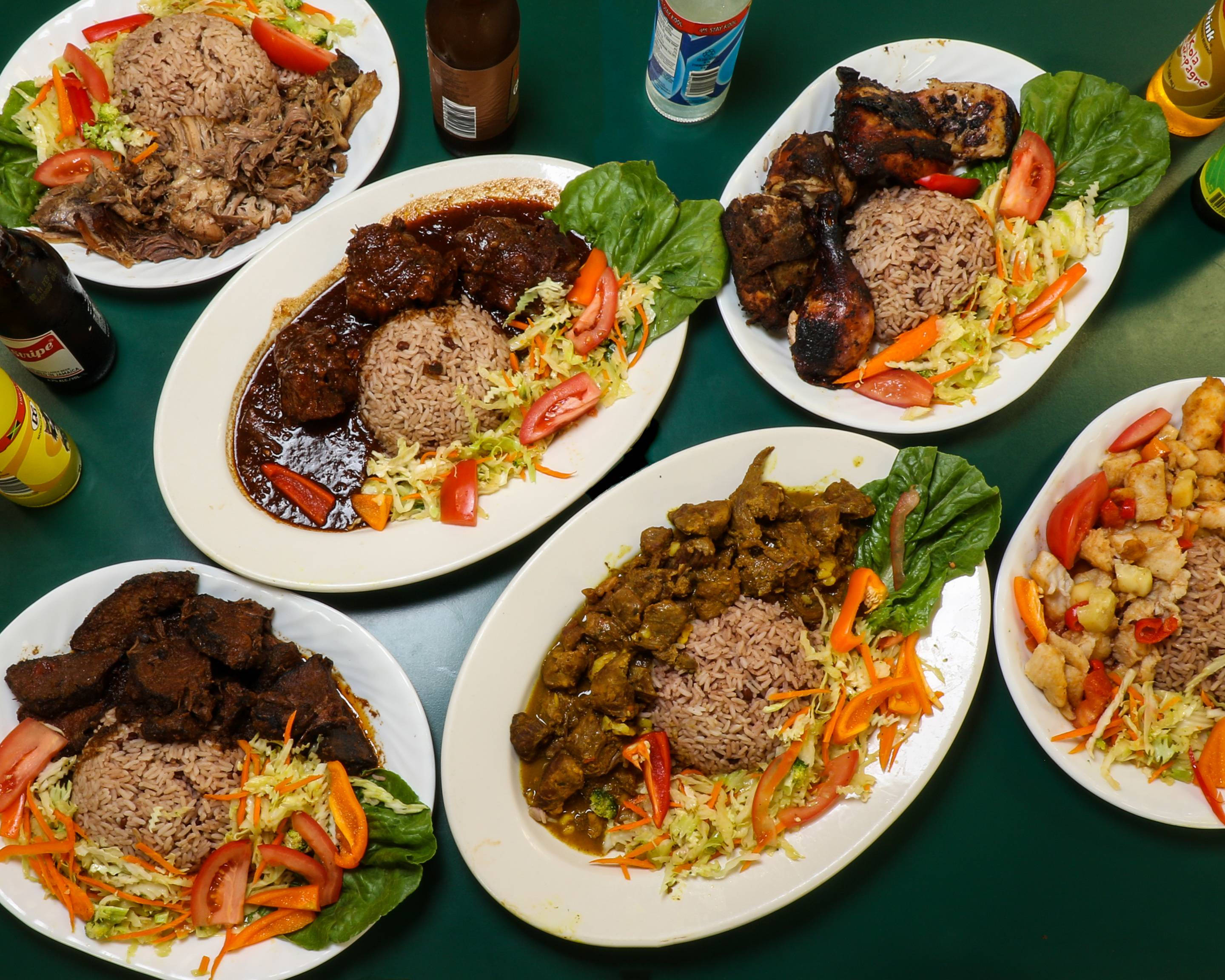 牙買加 桌布 壁紙 — 六盤香料豐富的肉類菜餚，搭配米飯和色彩繽紛的蔬菜，擺放在深綠色桌子上。