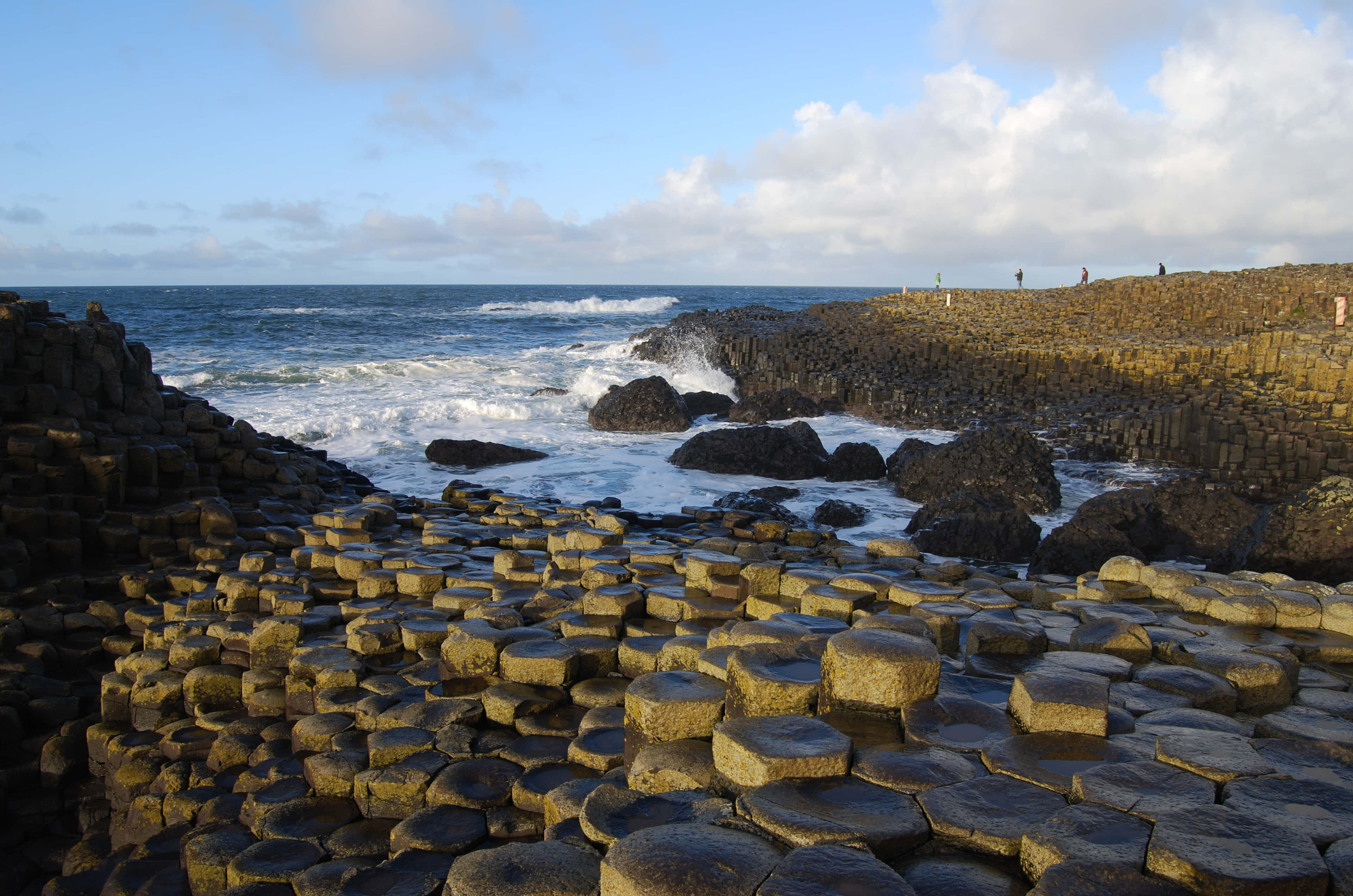 Blue Sky 桌布 壁紙 — 六角形玄武岩柱在巨人堤道從海洋中升起，天空部分多雲。