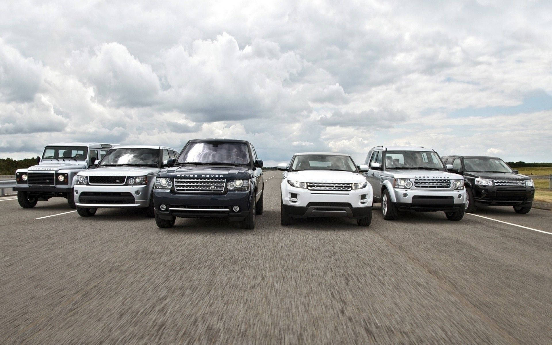 荒原路華 桌布 壁紙 — 六輛銀色、黑色和白色的 Land Rover SUV 在陰天的高速公路上排成一排。