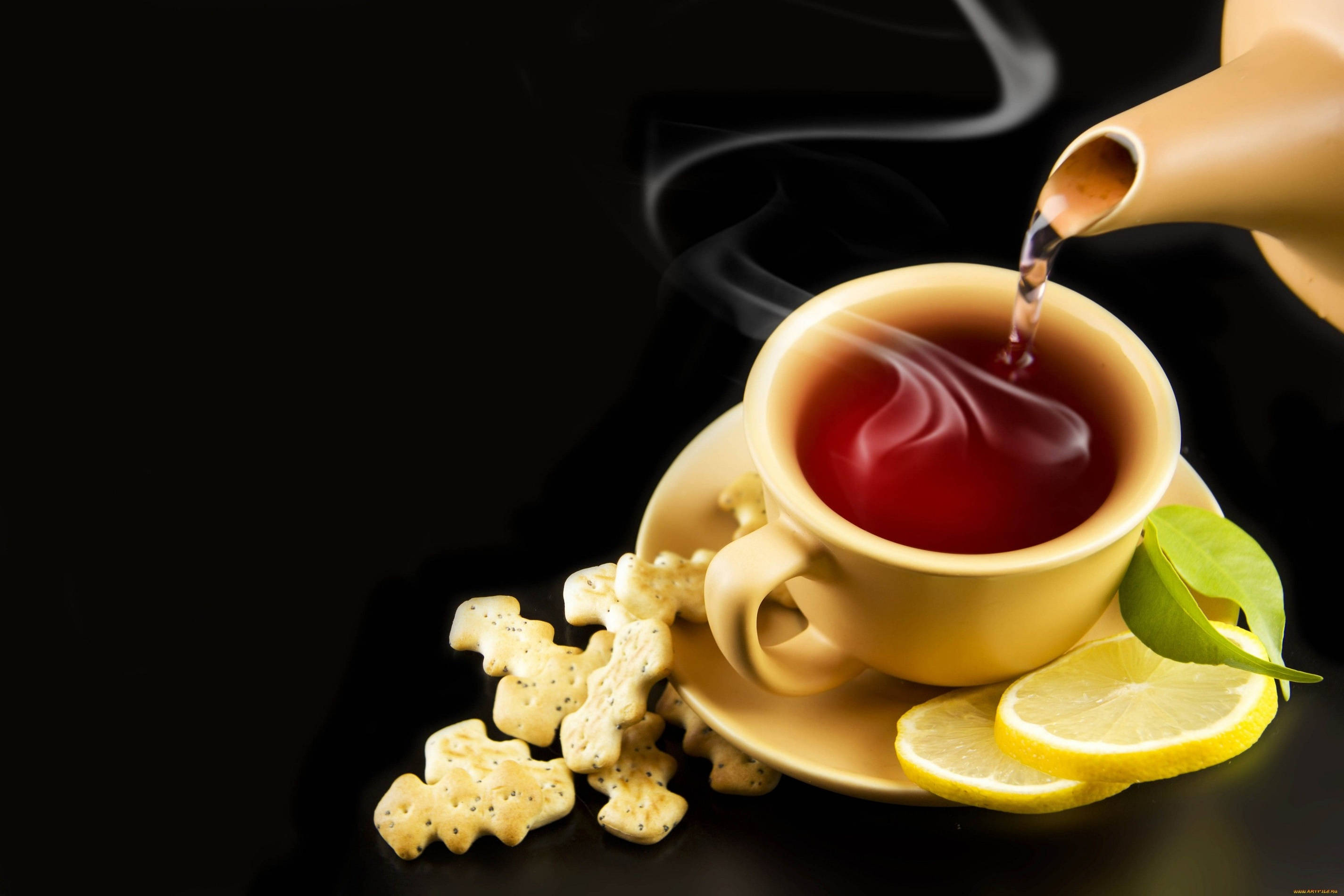 檸檬 桌布 壁紙 — 冒煙的熱茶倒入一個米色杯子中，旁邊有檸檬片和動物形狀的餅乾，放在黑色表面上。