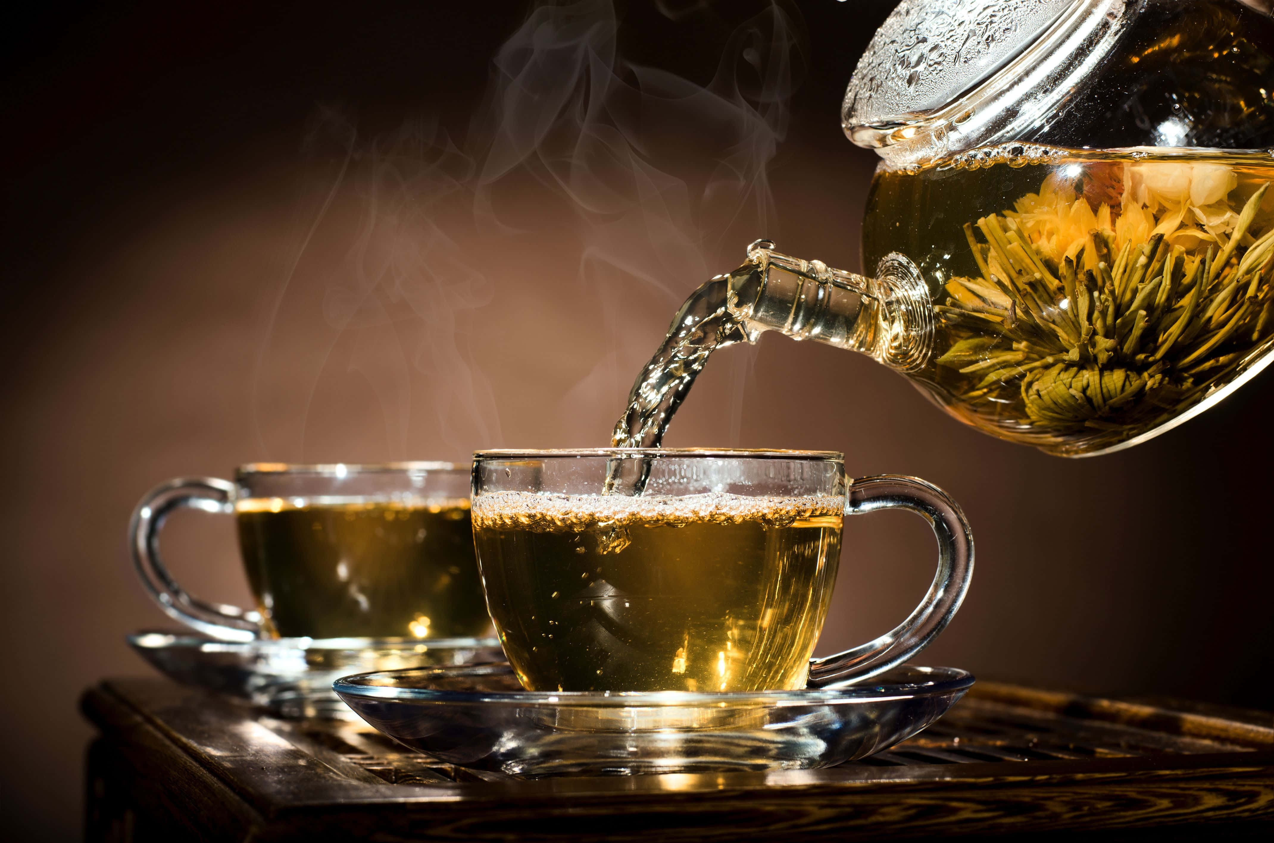 咖啡動圖 桌布 壁紙 — 冒煙的金色菊花茶從玻璃茶壺倒入木托盤上的透明杯中。